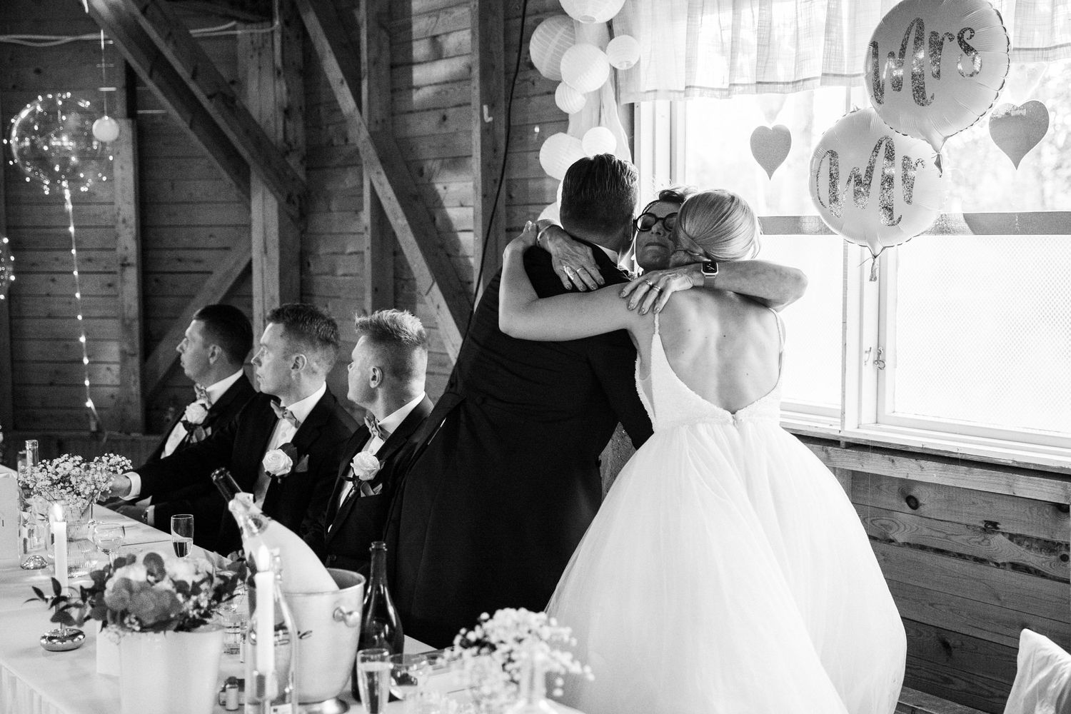 Black and white reception scene with decorative balloons and string lights in rustic barn venue.
