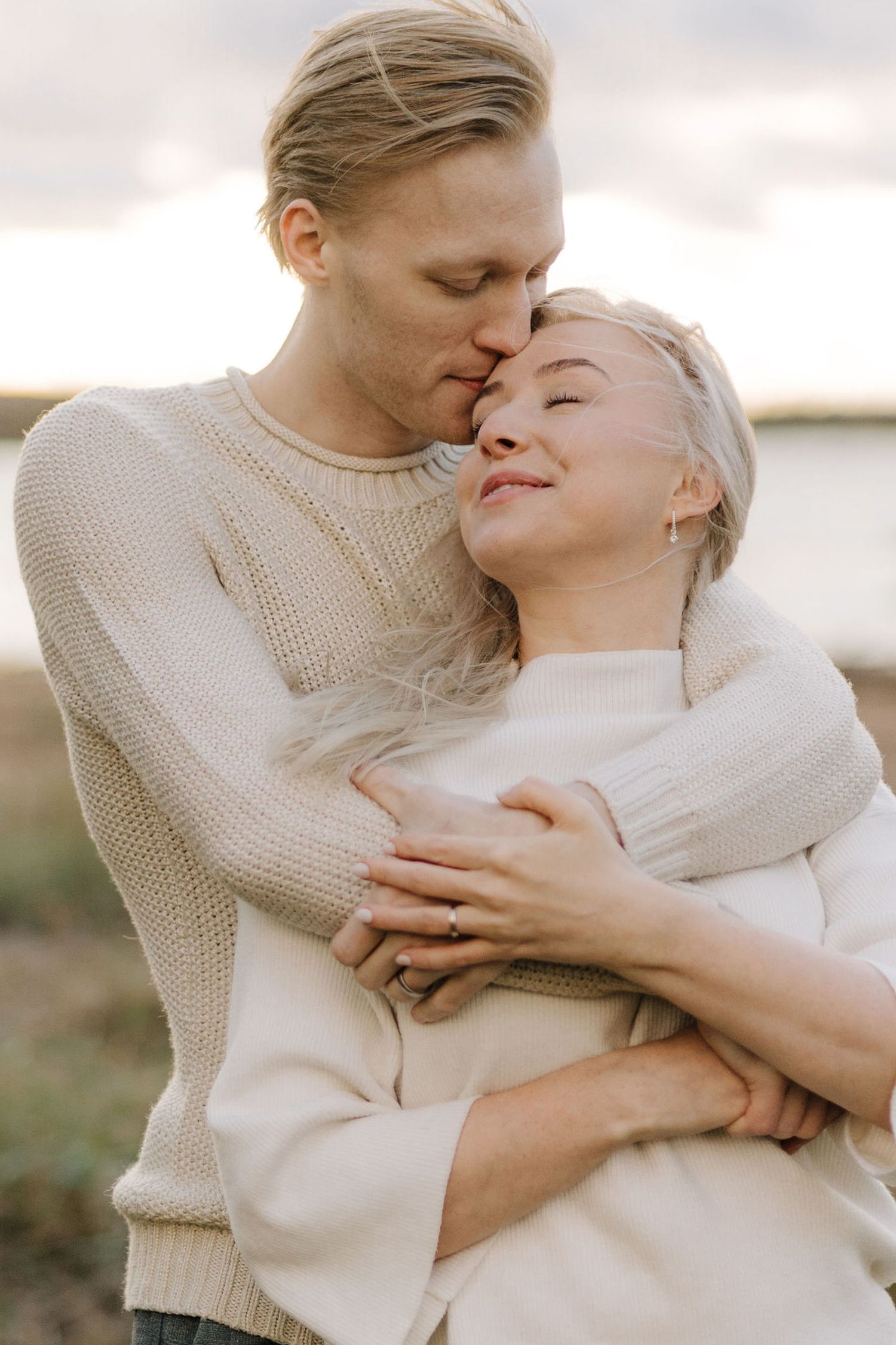 Intimate moment between couple in matching neutral sweaters sharing a gentle embrace.