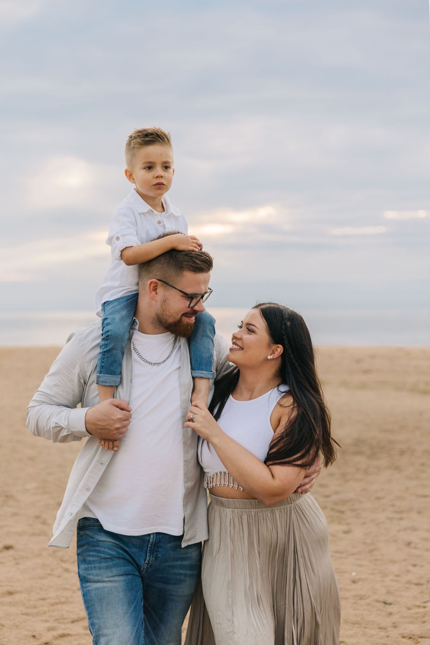 Family sharing a joyful moment together on a sandy beach during sunset.