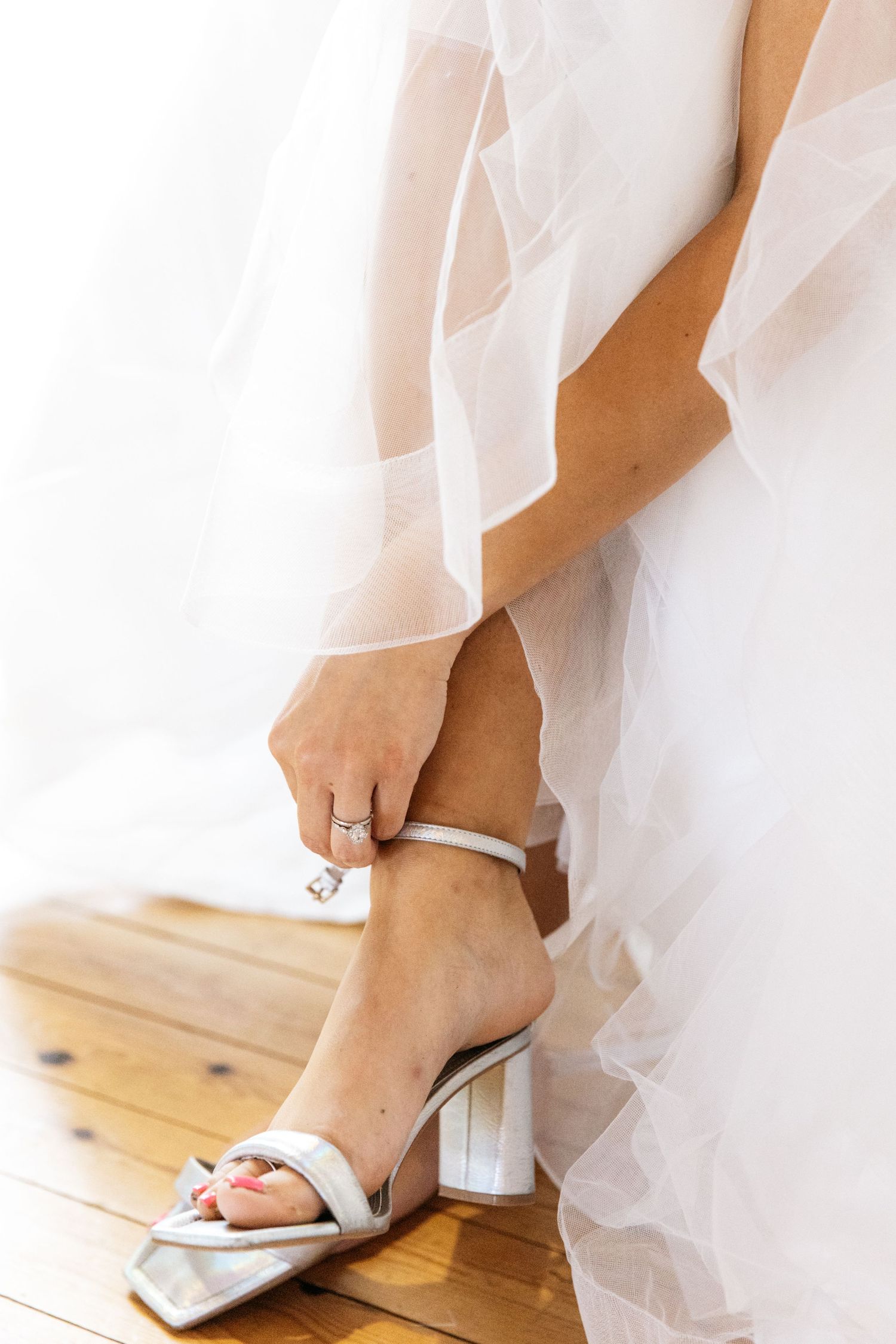 Close-up of bride's foot in elegant white block heel sandal with tulle dress flowing.