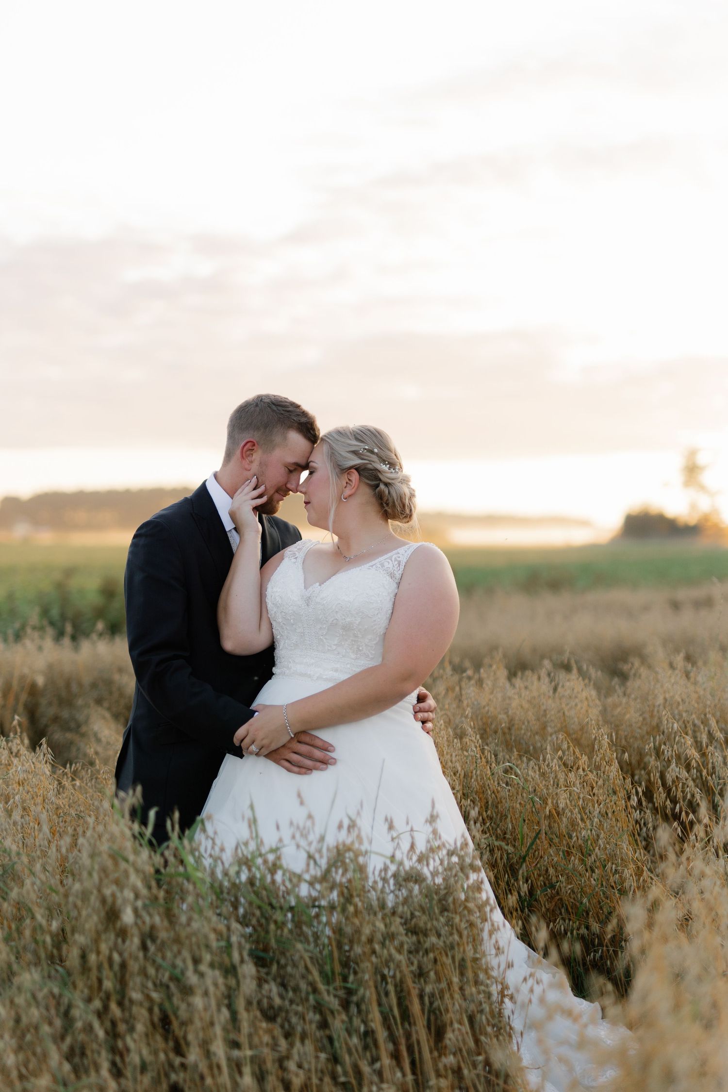 An intimate moment between newlyweds in a sun-drenched field at golden hour.
