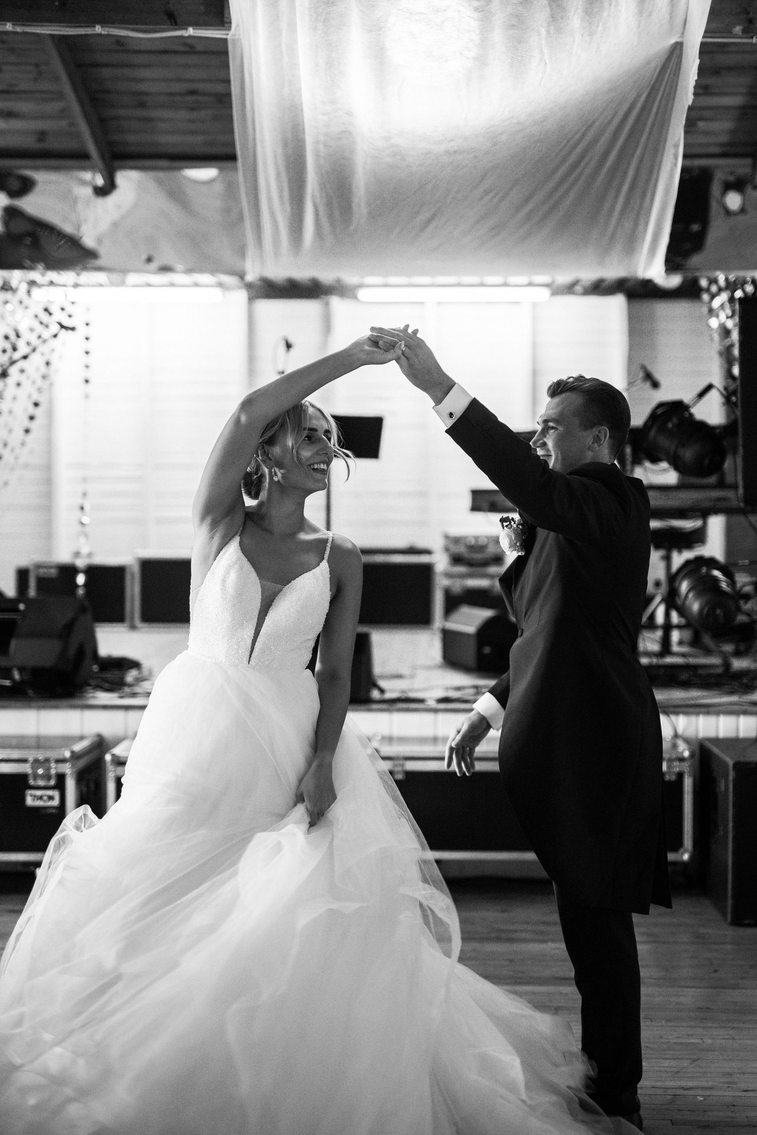 Black and white photo of dancing couple twirling during their wedding celebration.