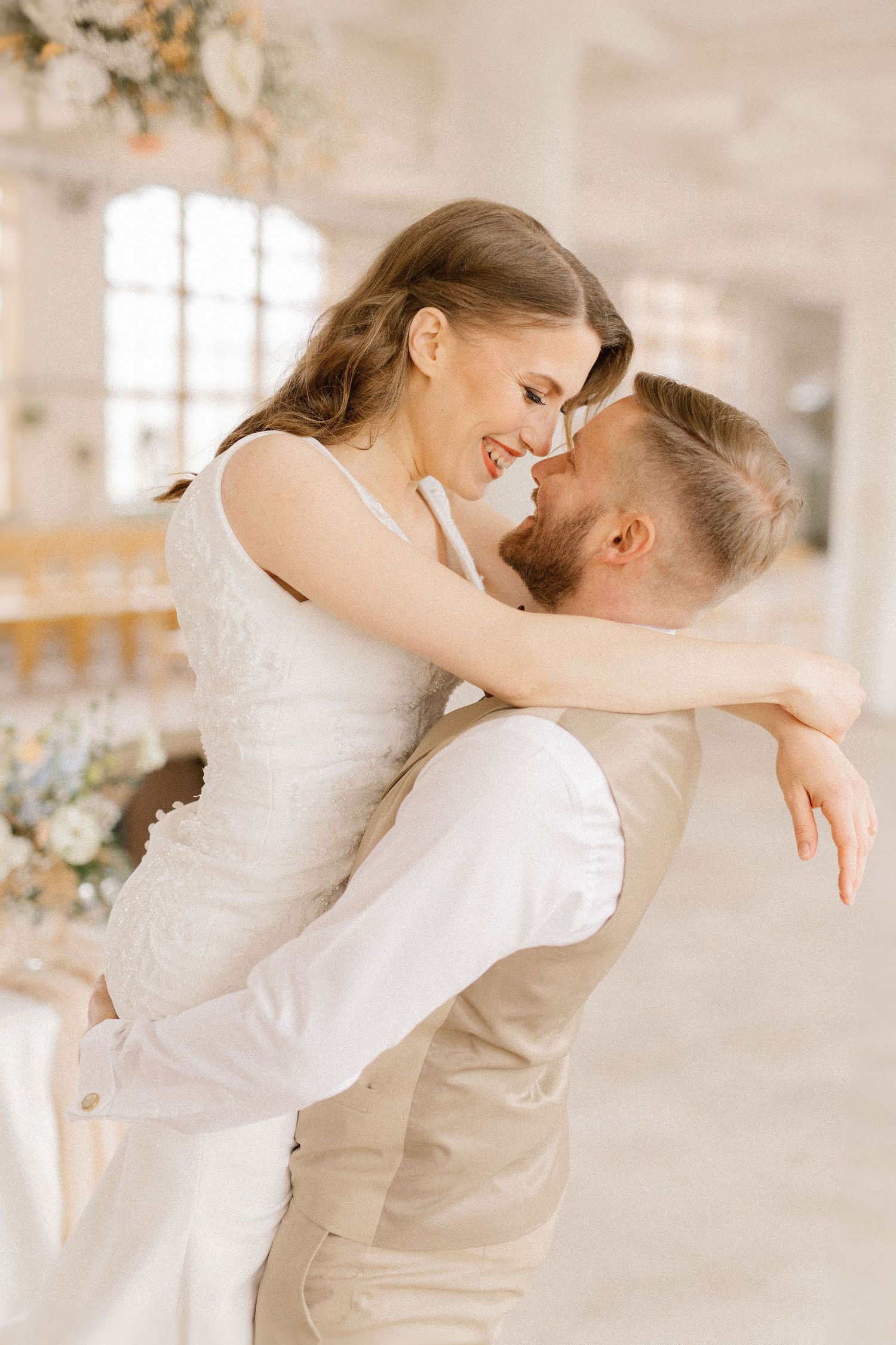 Joyful couple sharing intimate moment in elegant white venue.
