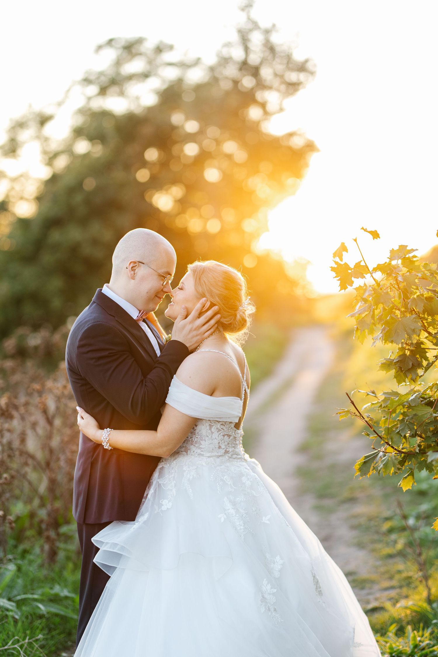 Wedding couple embracing during golden hour sunset in a vineyard setting.