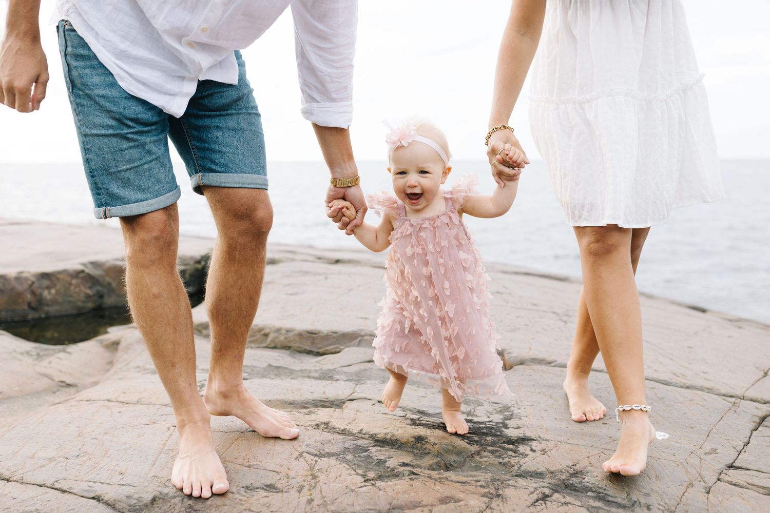 Close-up view of bare feet walking together on a sandy beach at sunset.