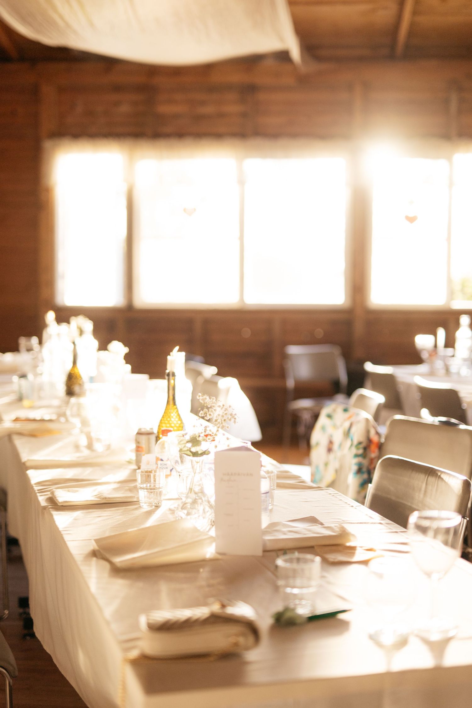 An elegant wedding reception table setting with soft natural light streaming through windows.
