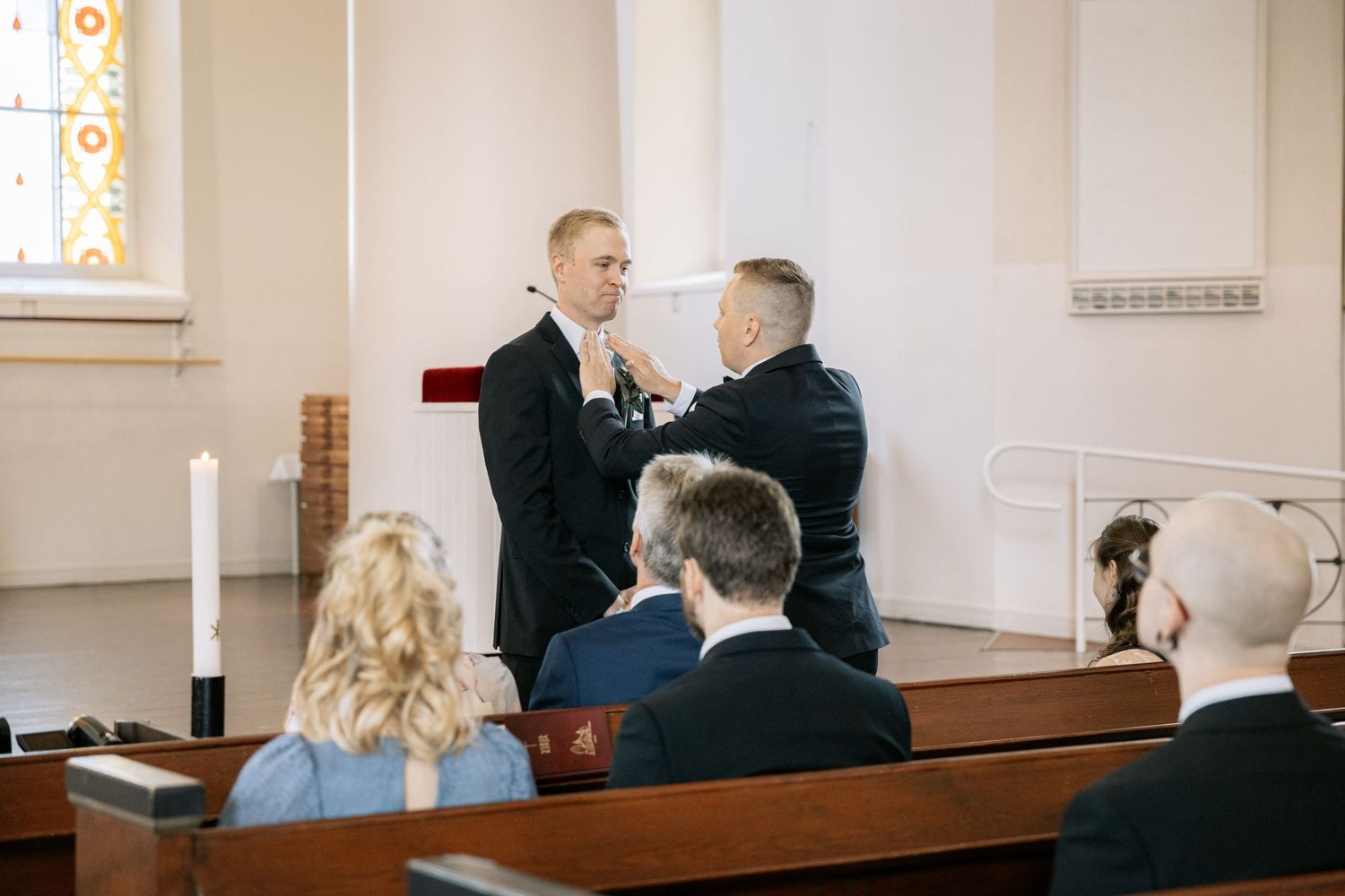 Wedding ceremony in a bright church interior with wooden pews.