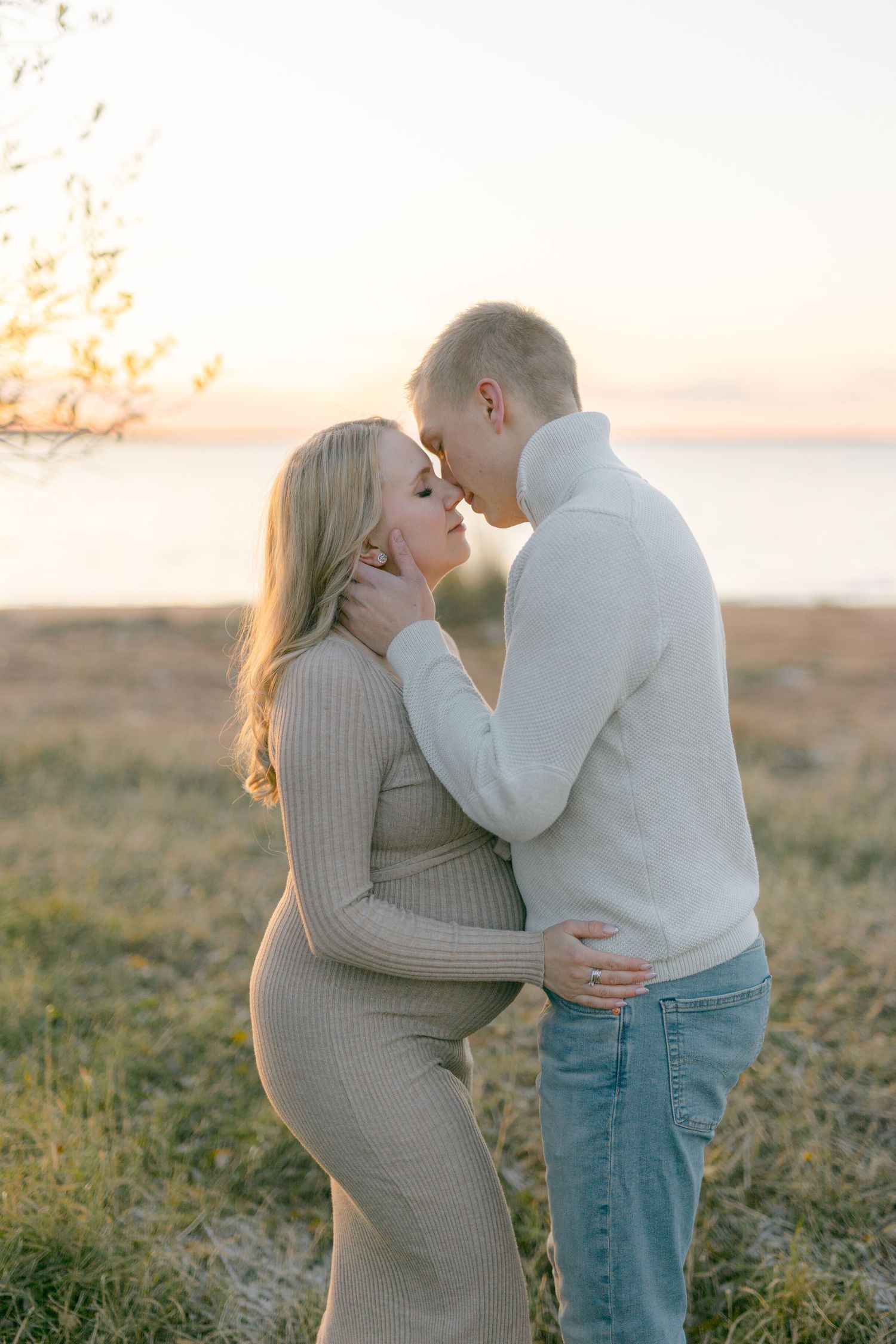 Loving couple sharing tender moment during sunset maternity photoshoot.