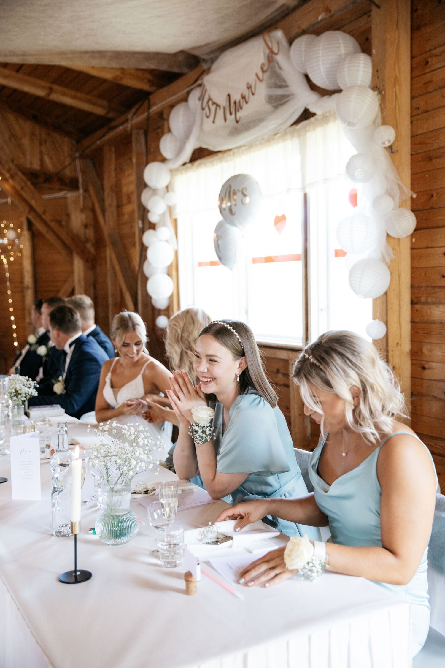Wedding reception table with guests enjoying the celebration in rustic barn setting.