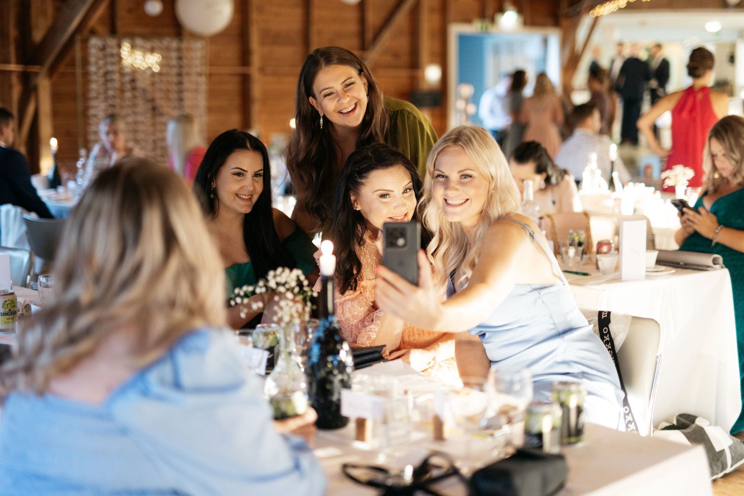 A lively group of friends laughing and celebrating together at a restaurant table during a special occasion.