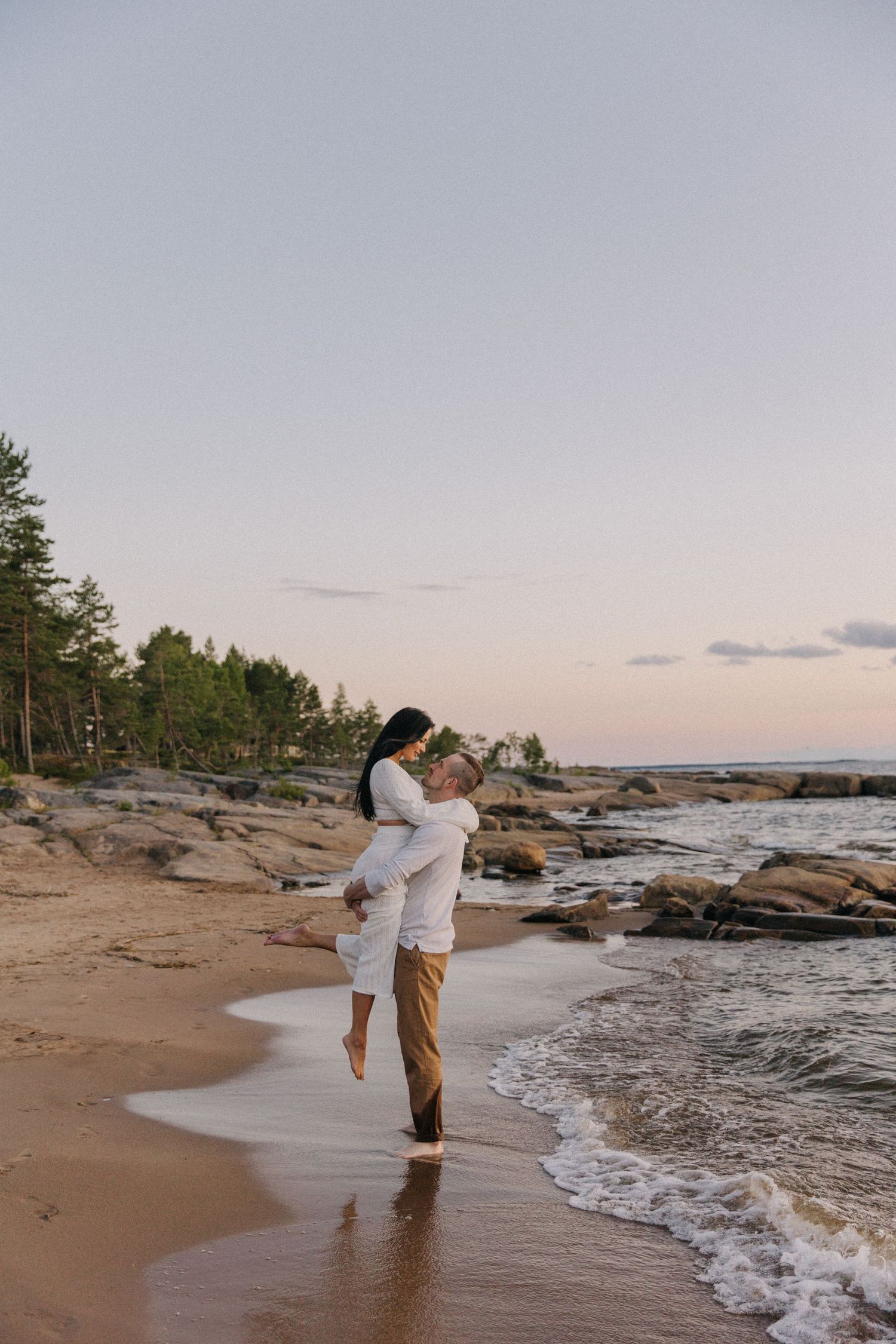 Romantic beachside moment with couple embracing on sandy shore at dusk.