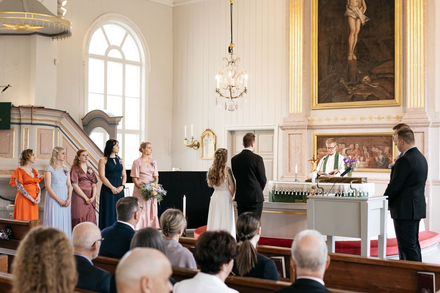 Church wedding ceremony in progress with ornate architecture and chandelier visible.