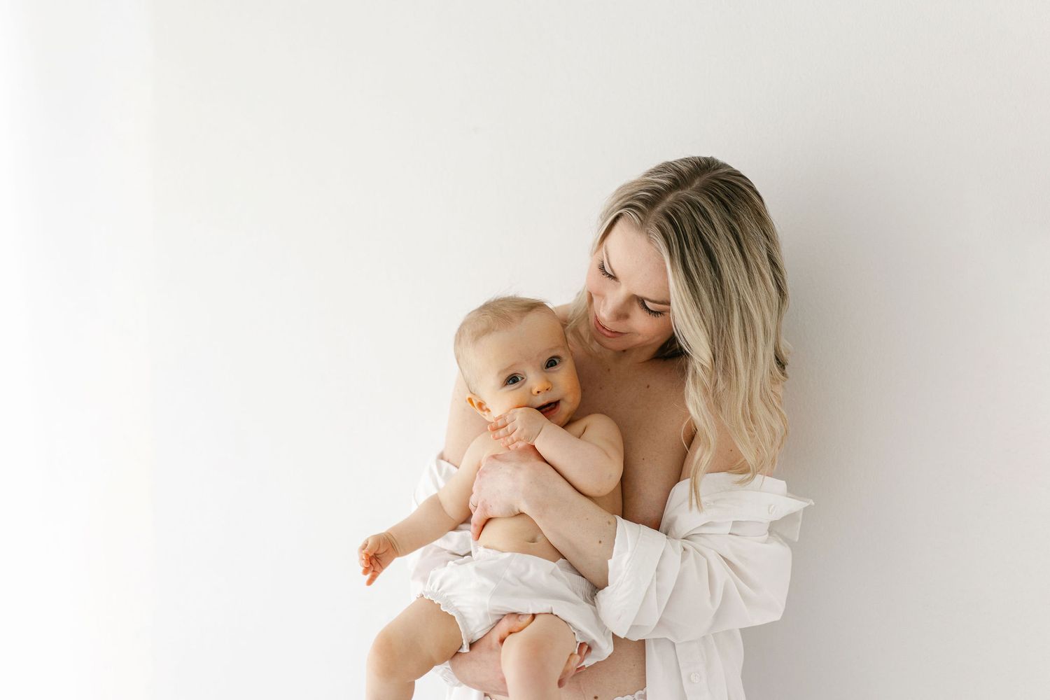 Intimate mother and baby portrait against white background in soft natural light.