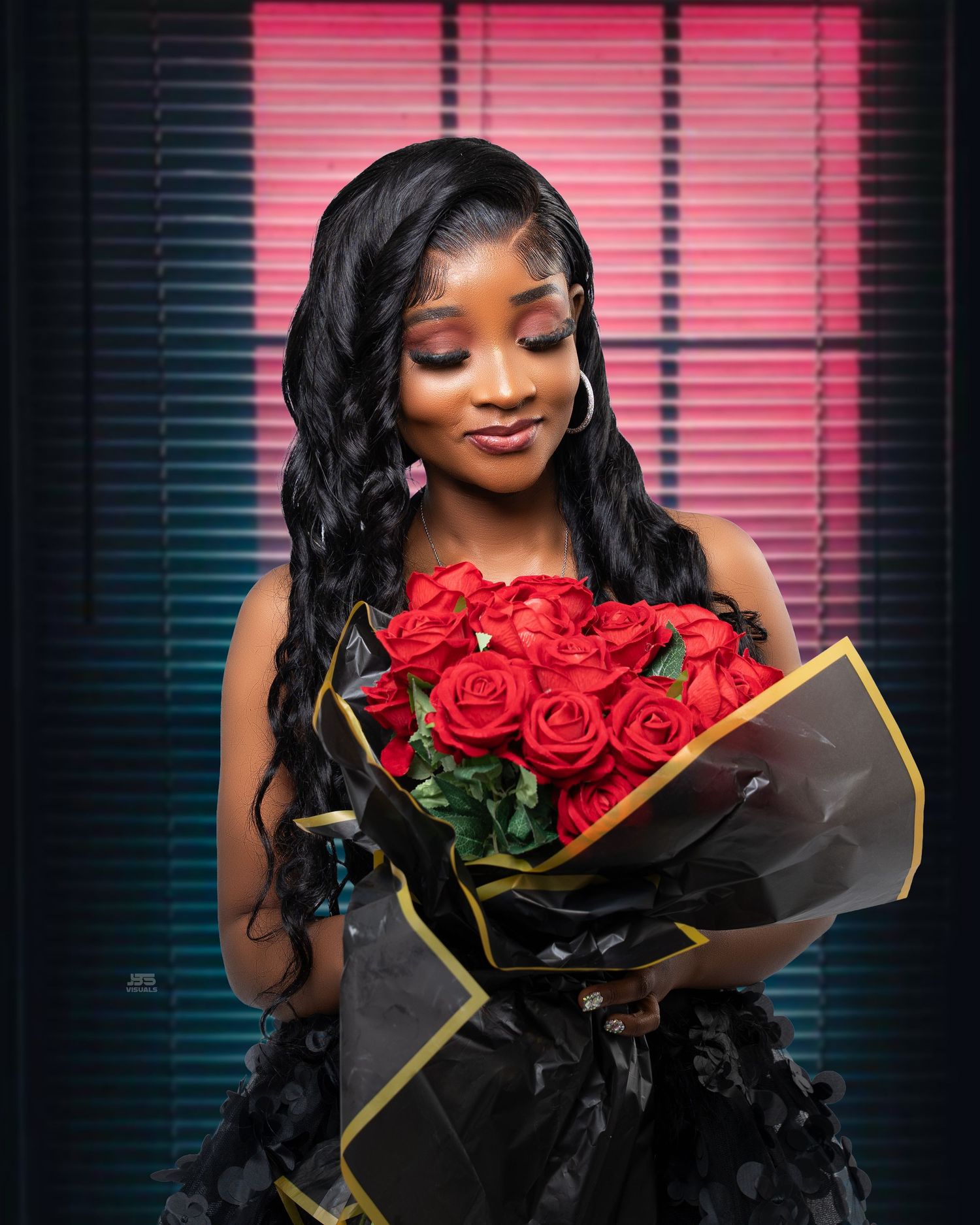Beautiful woman in black dress holds bouquet of red roses under neon lights.