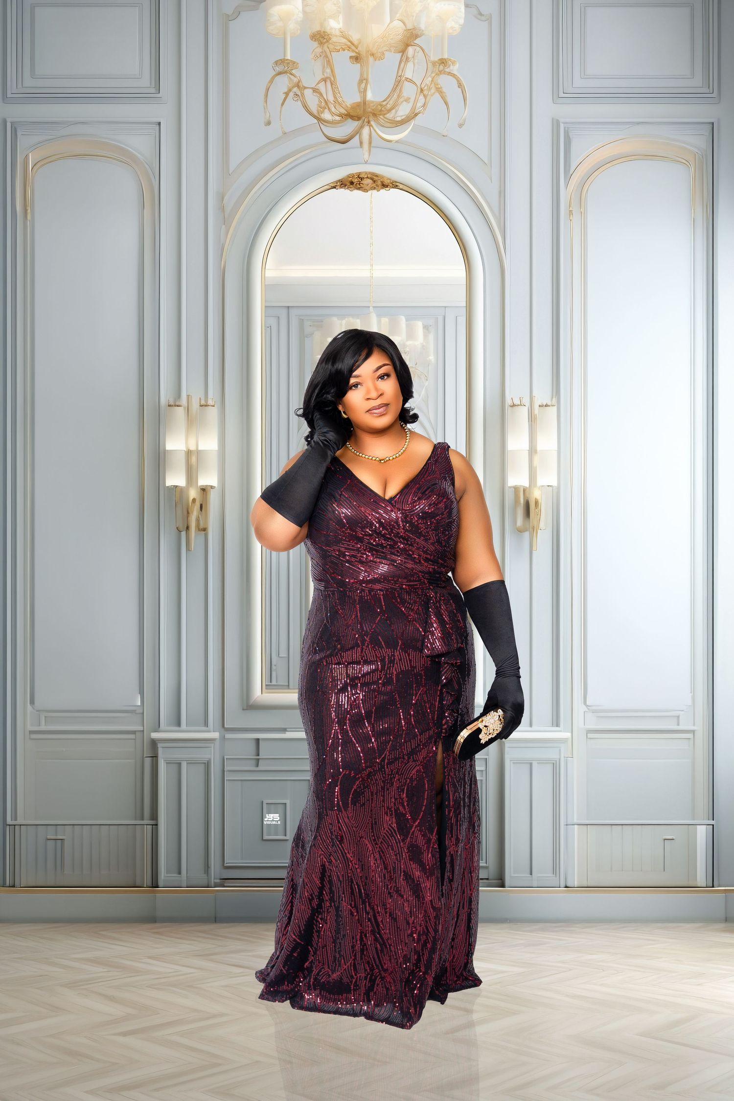Woman in burgundy sequin gown with black gloves posing in elegant white paneled room with chandelier.
