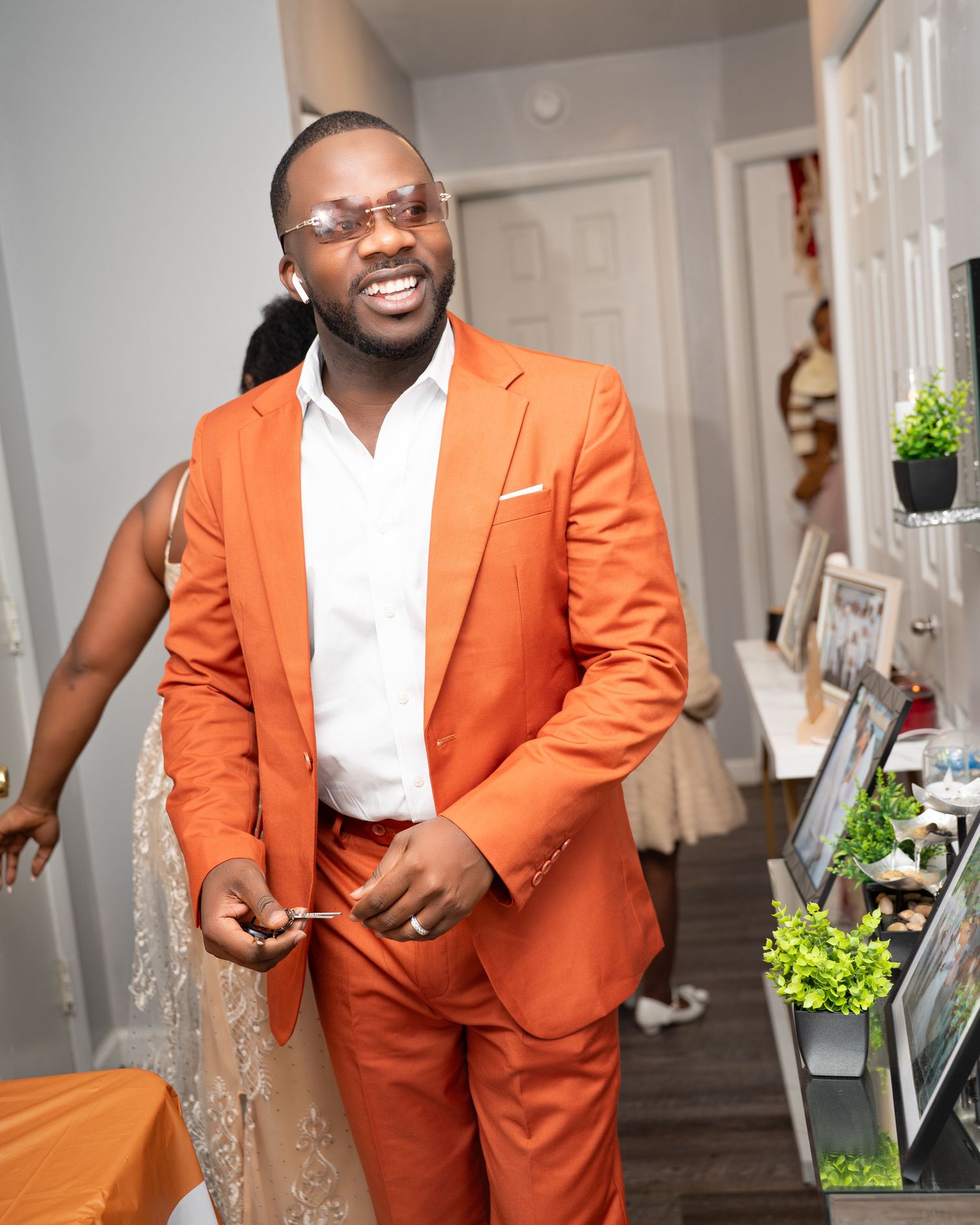Man in bright orange suit smiling at an indoor celebration event.