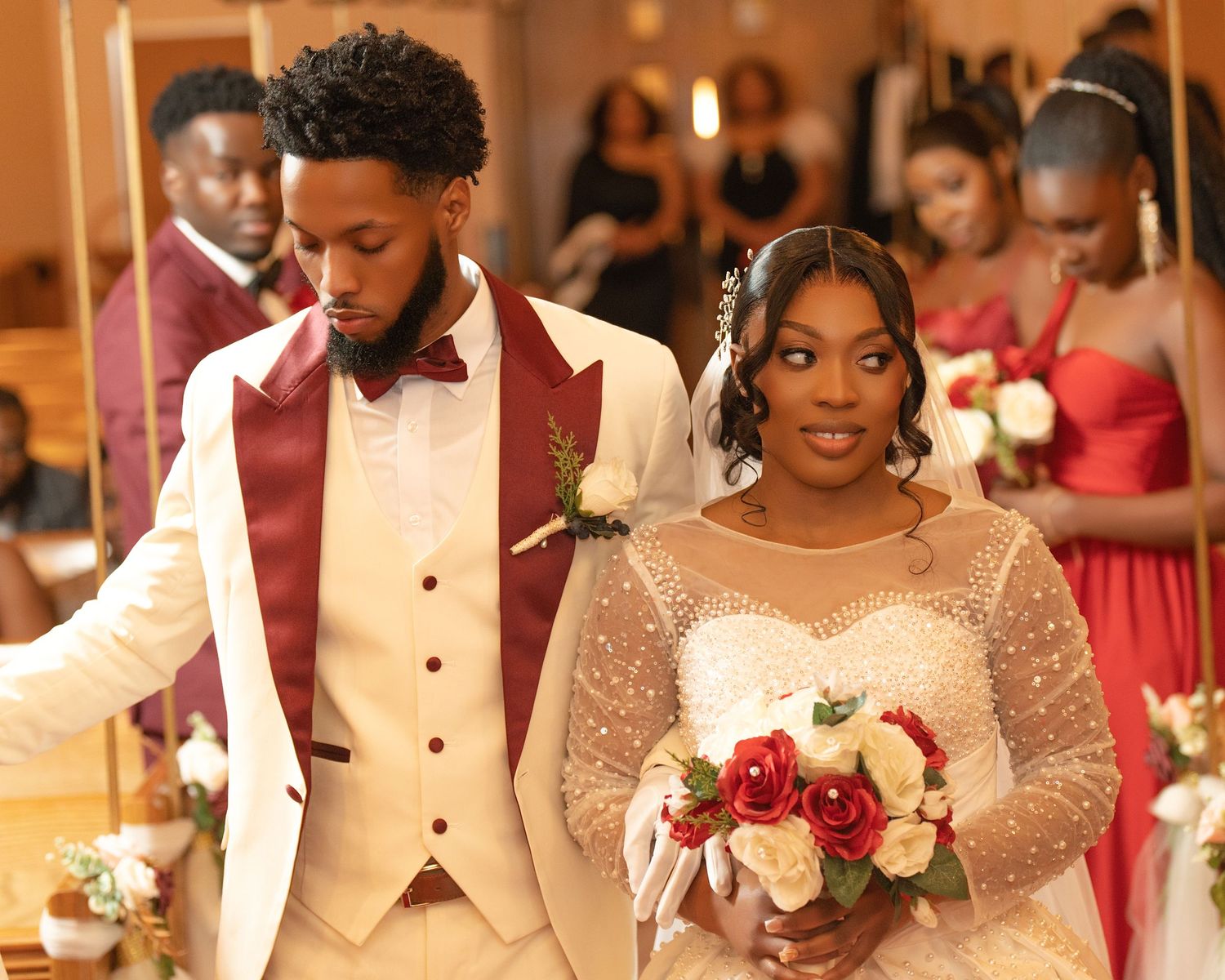 Newlywed couple walks down aisle in church wedding, groom in ivory tuxedo, bride in beaded gown.