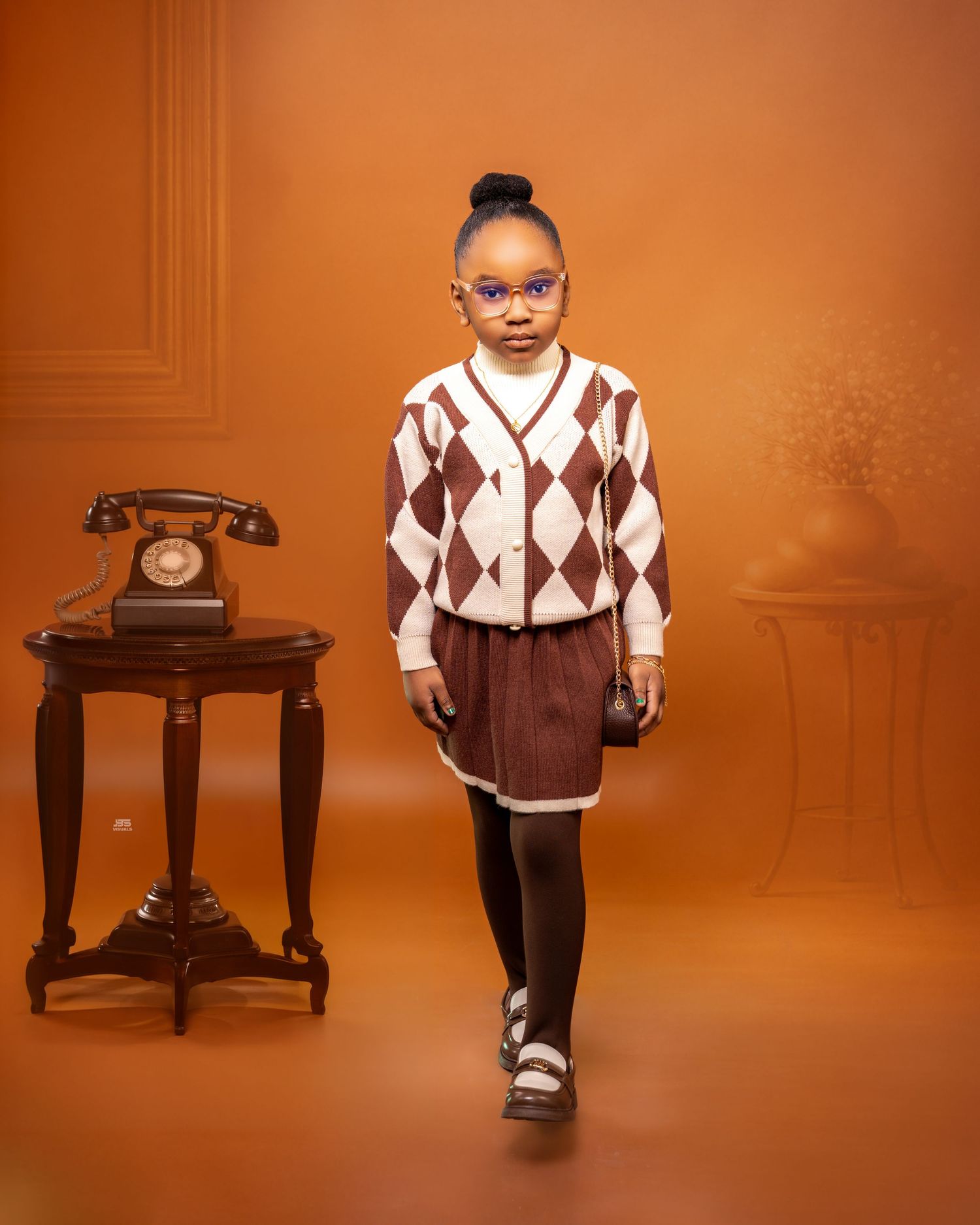 Young girl in argyle sweater and brown skirt walking confidently in retro photo studio.