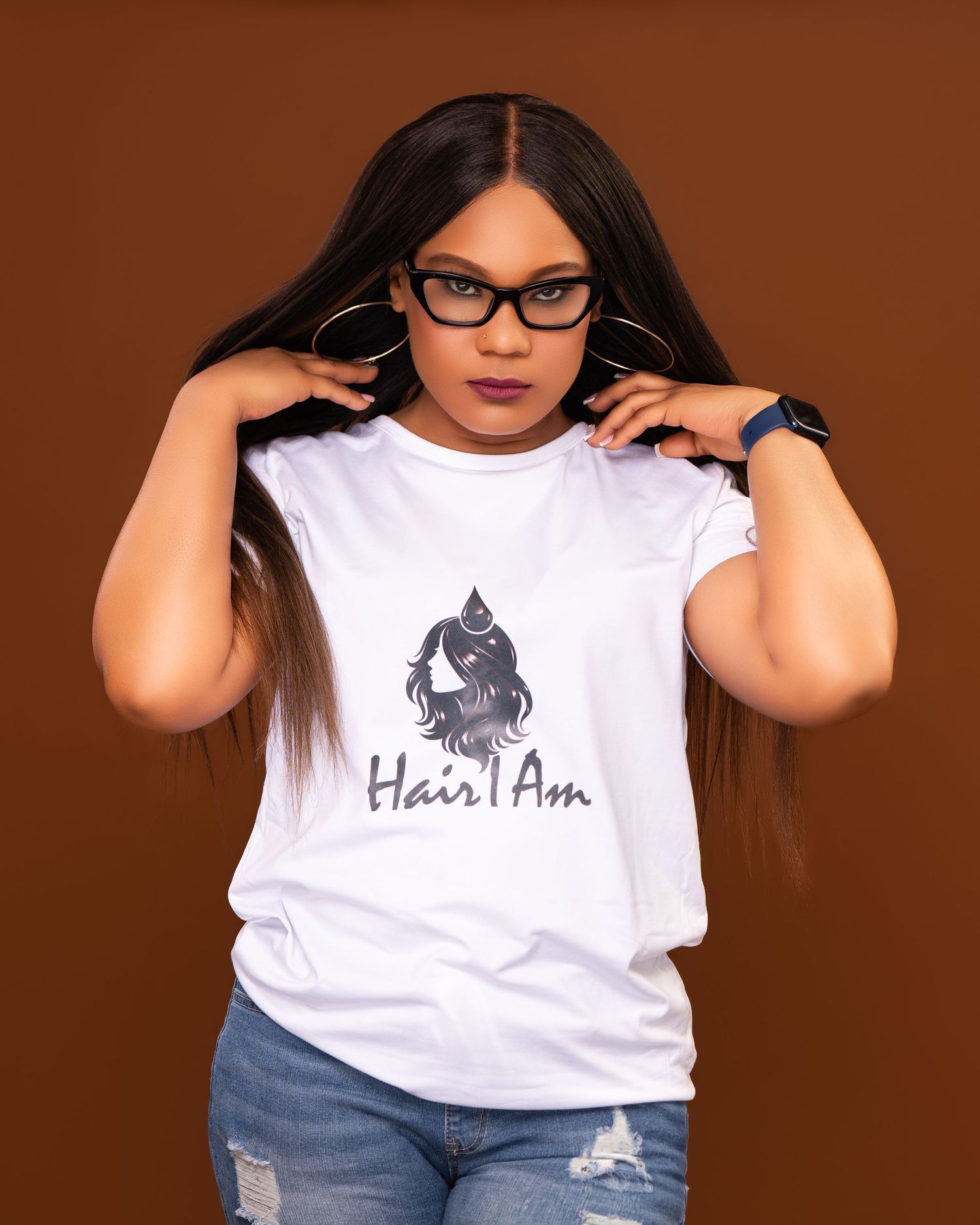 Woman modeling Hair I Am branded white t-shirt with long straight hair and glasses.