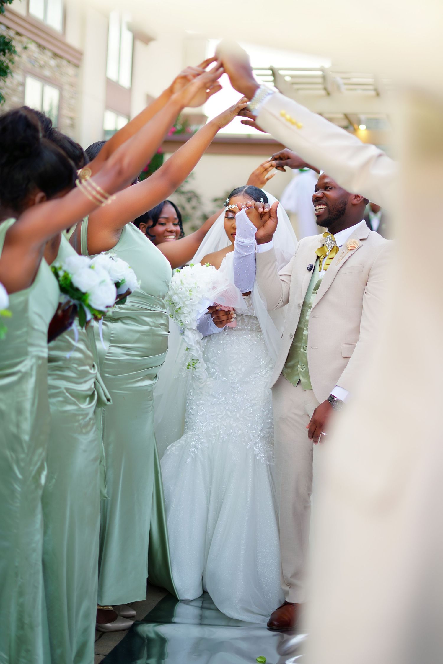 Joyful bride and groom walking through cheering bridesmaids in mint green dresses during wedding celebration.