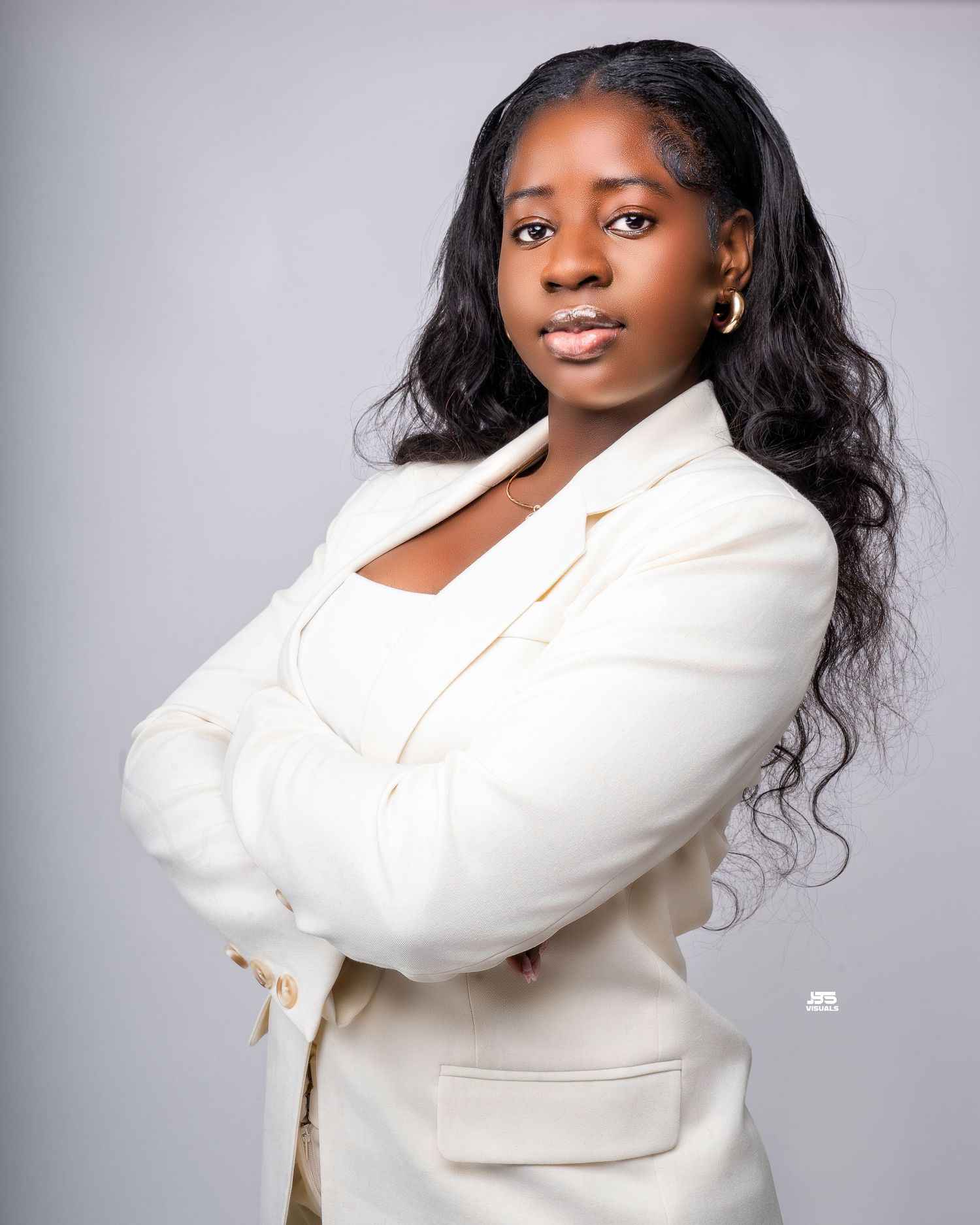 Confident woman in white blazer with arms crossed posing for a professional portrait.