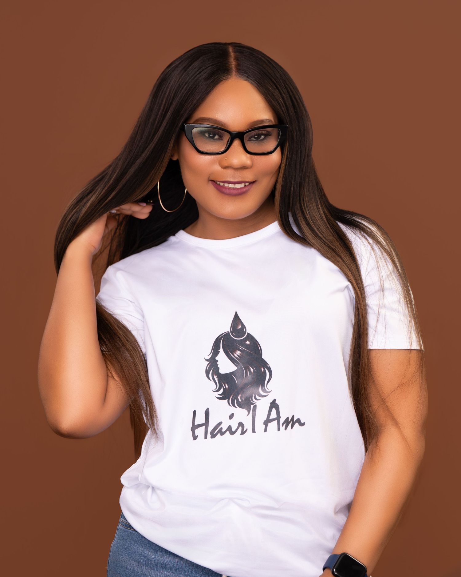 Smiling woman in Hair I Am white t-shirt posing with long straight hair and glasses.