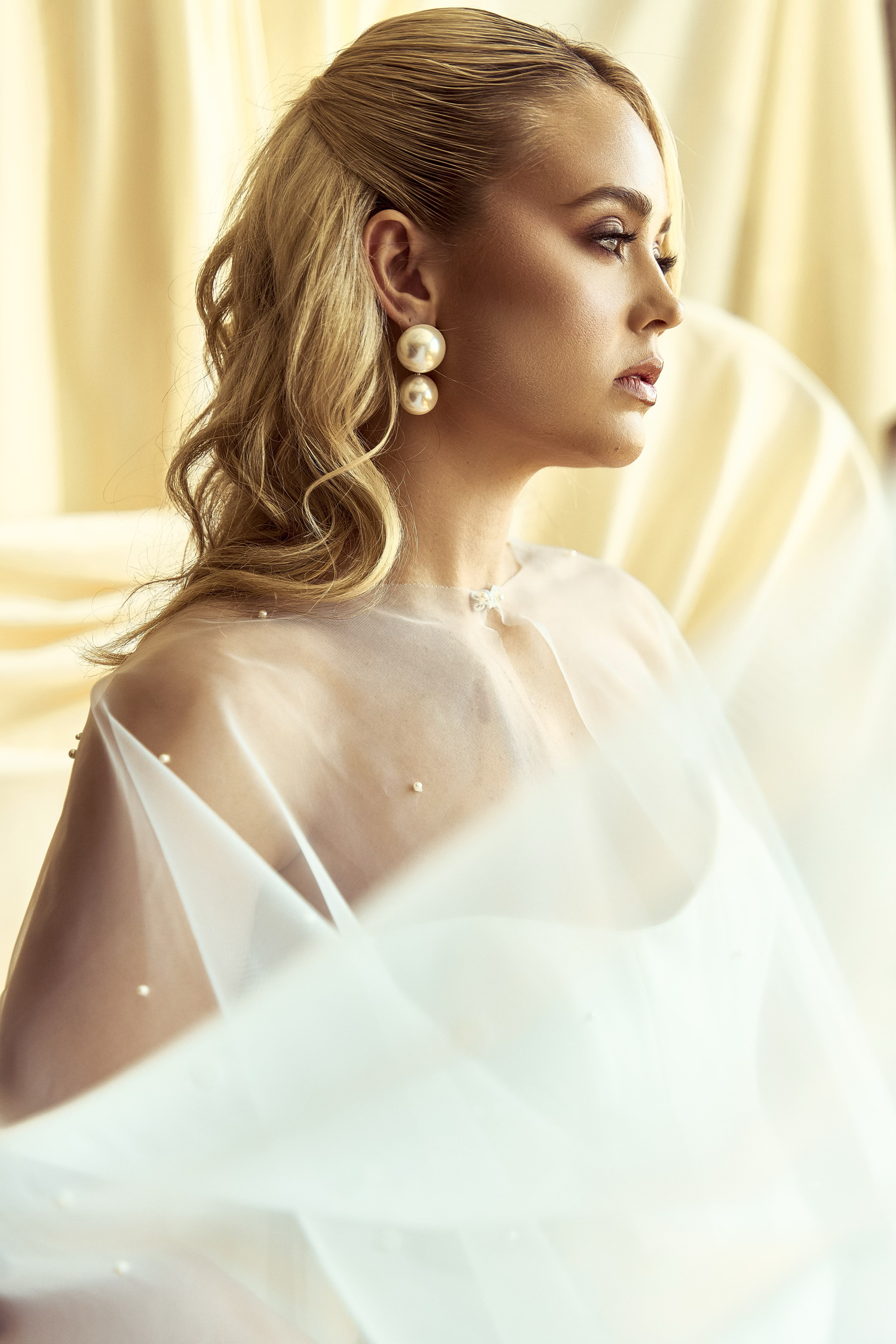 Artistic portrait series showing ethereal profile views against soft cream curtains with flowing white fabric movement.