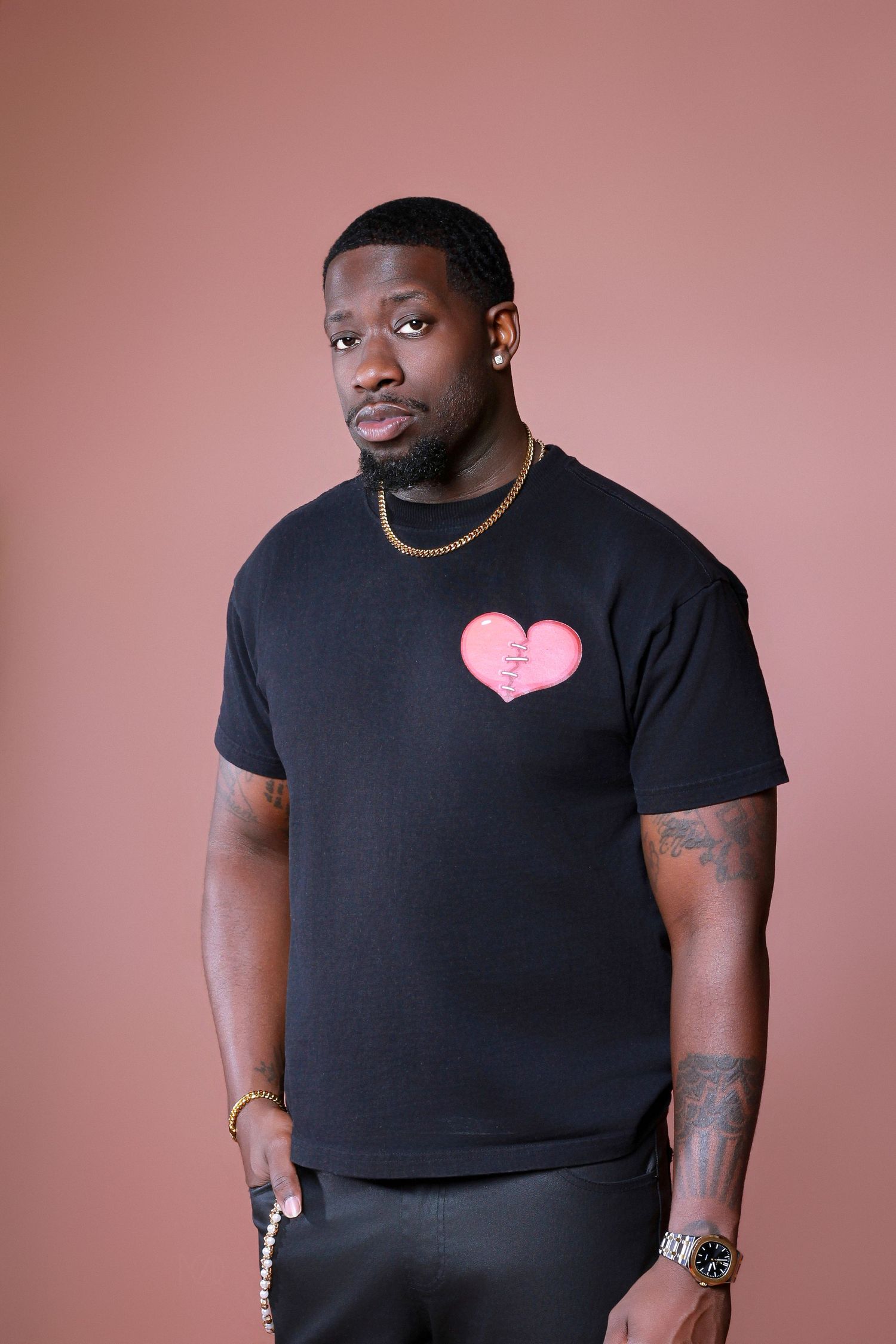 A series of fashion portraits showing someone wearing a black t-shirt against a pink backdrop in various poses.