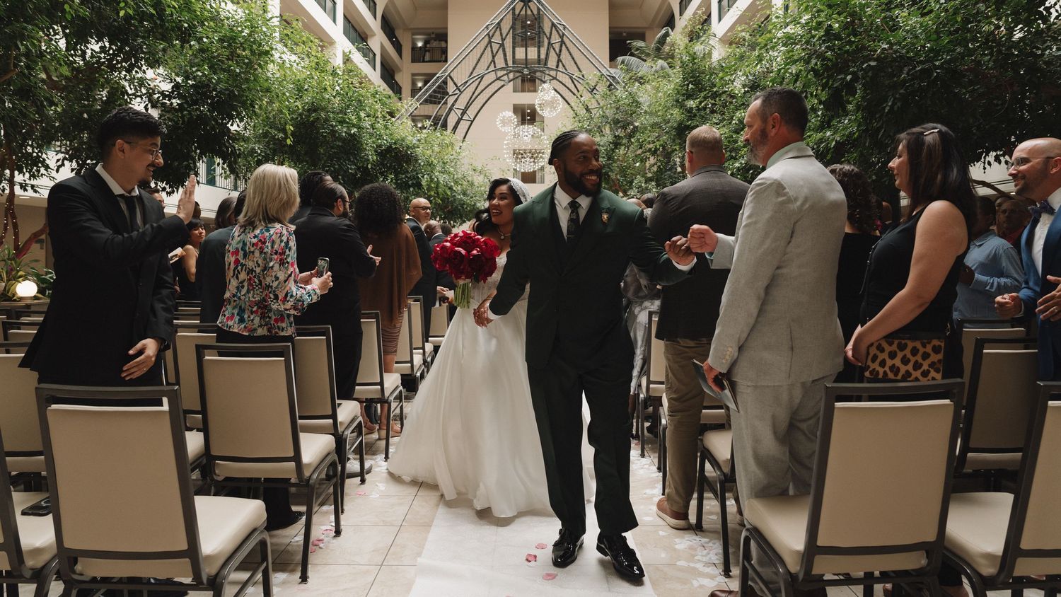 Newlyweds walk back down the aisle together after their indoor garden wedding ceremony.