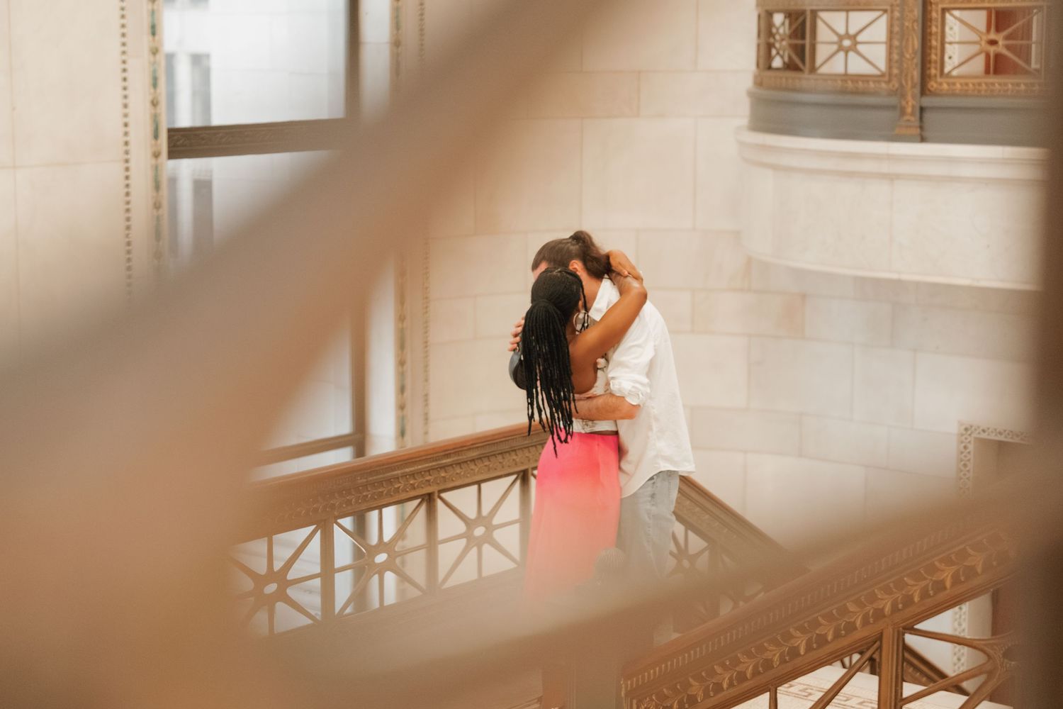Couple sharing a romantic kiss on a balcony inside an ornate historic building.