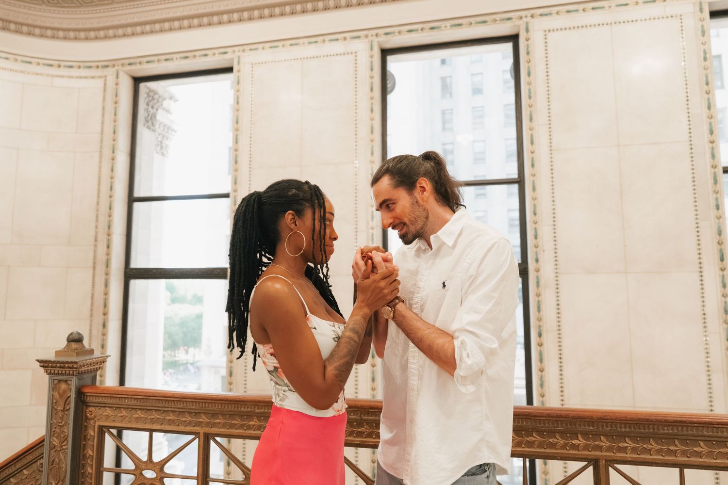 Happy interracial couple dancing and holding hands inside a beautiful ornate historic building.
