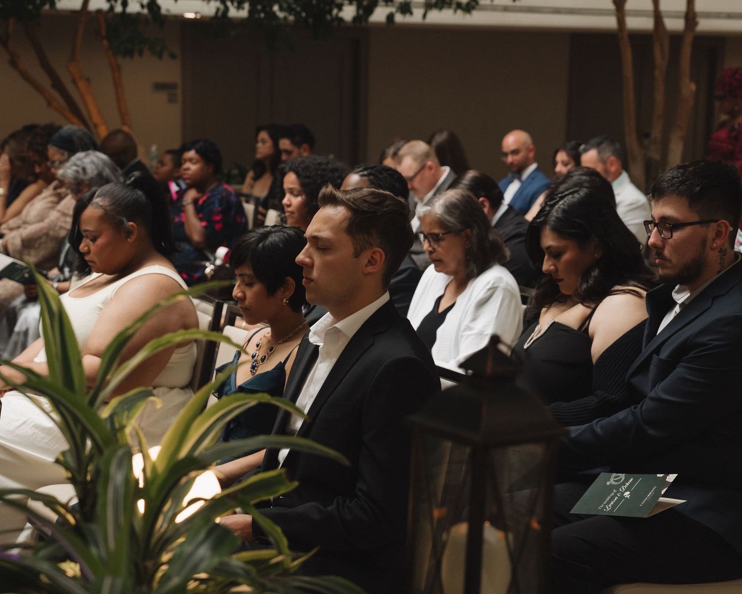 Guests seated in rows at a formal event, dressed in elegant black and white attire, attentively watching a ceremony.