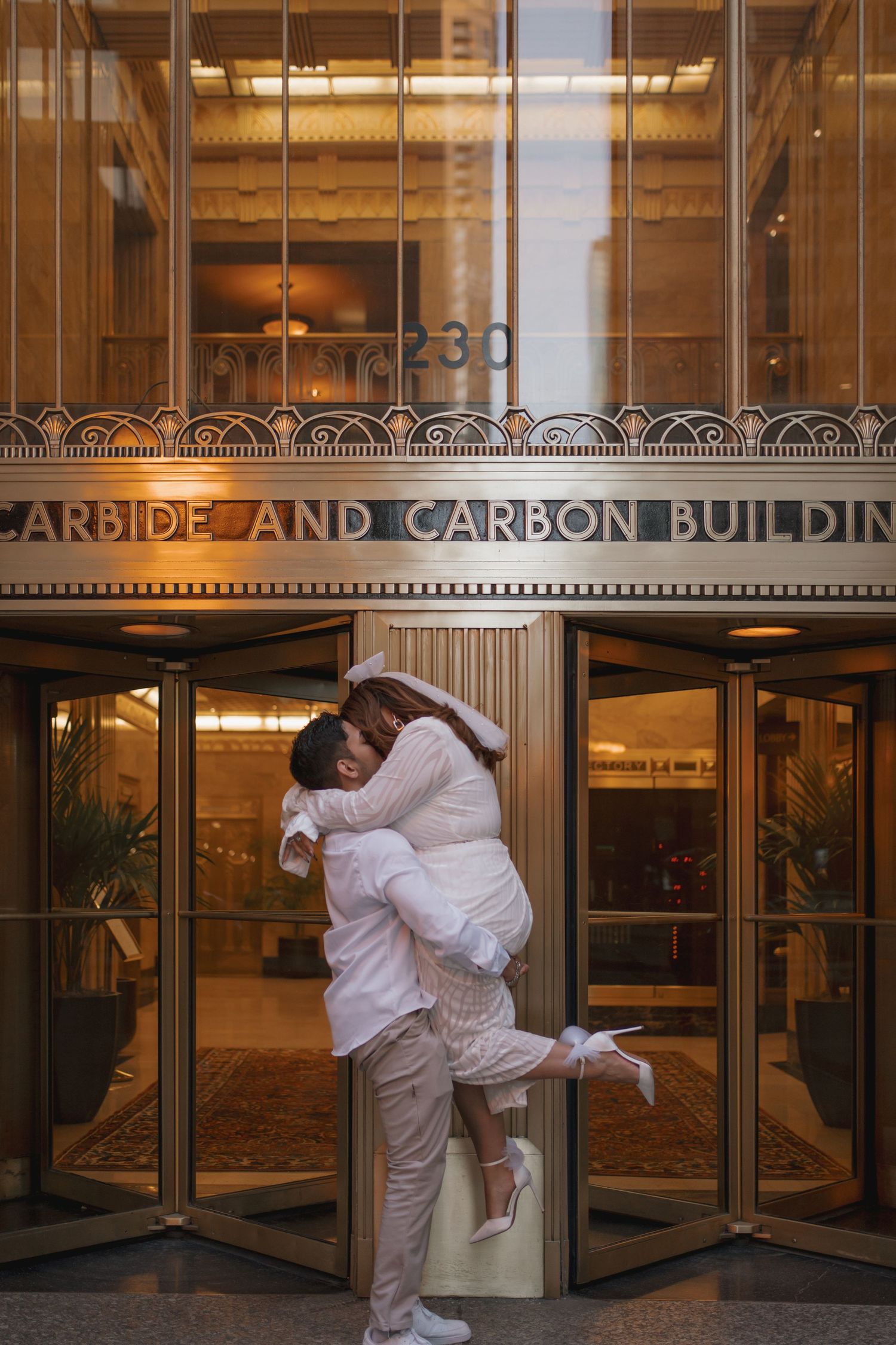 Couple sharing a romantic lift and embrace outside the historic Carbide and Carbon Building in Chicago.