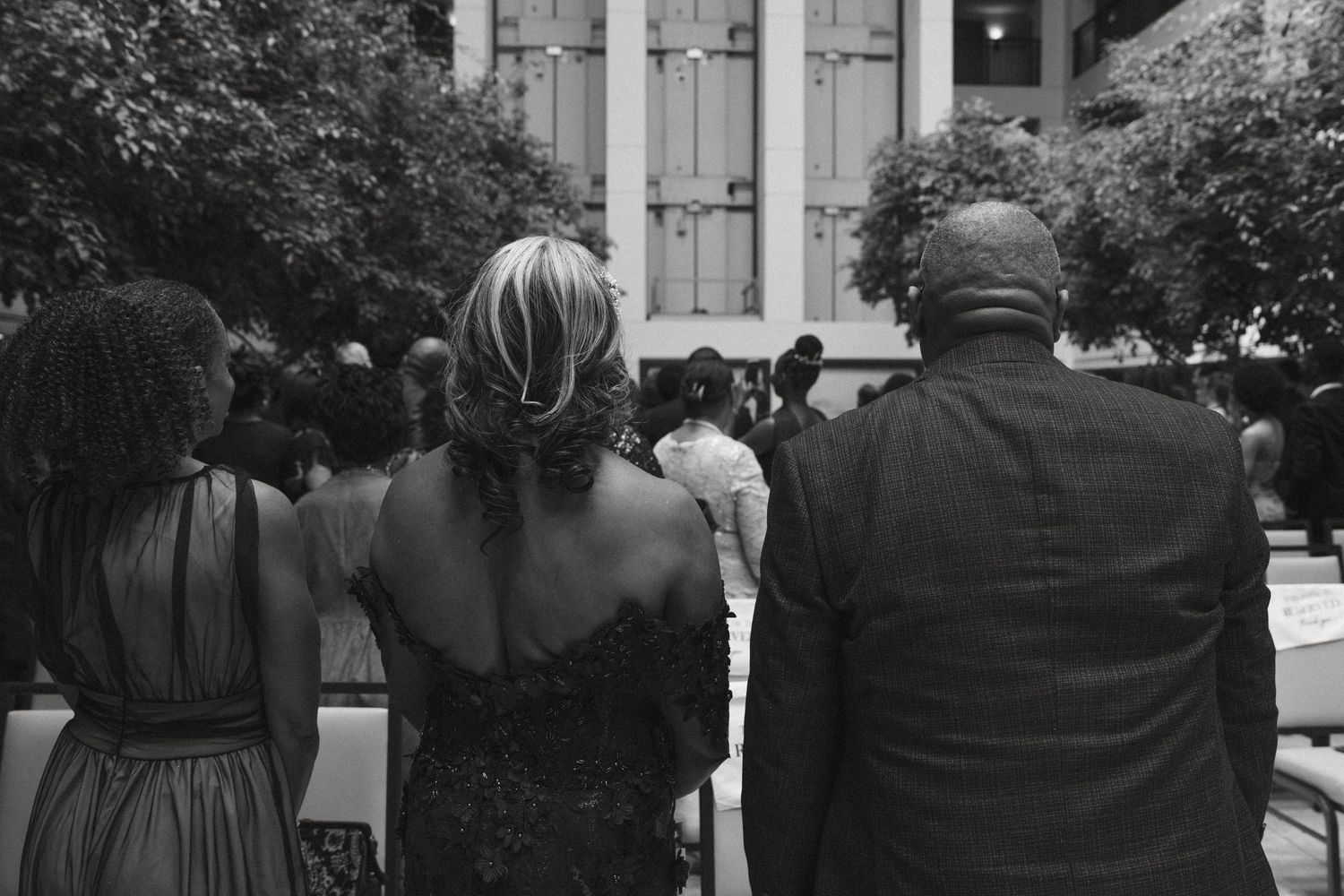 Black and white photo of wedding guests walking toward outdoor ceremony venue.
