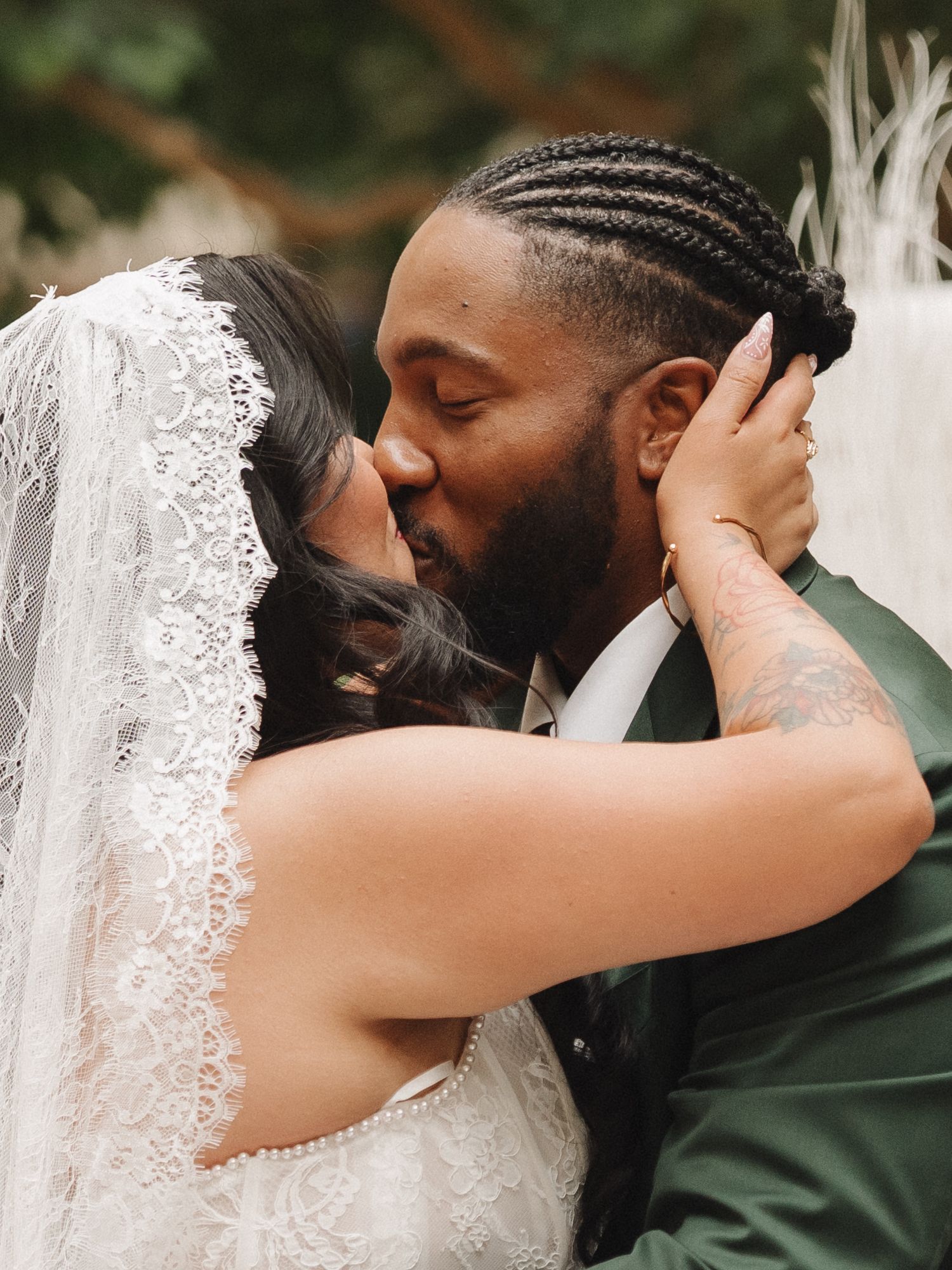 Bride and groom sharing a romantic first kiss at their wedding ceremony, bride wearing lace veil.