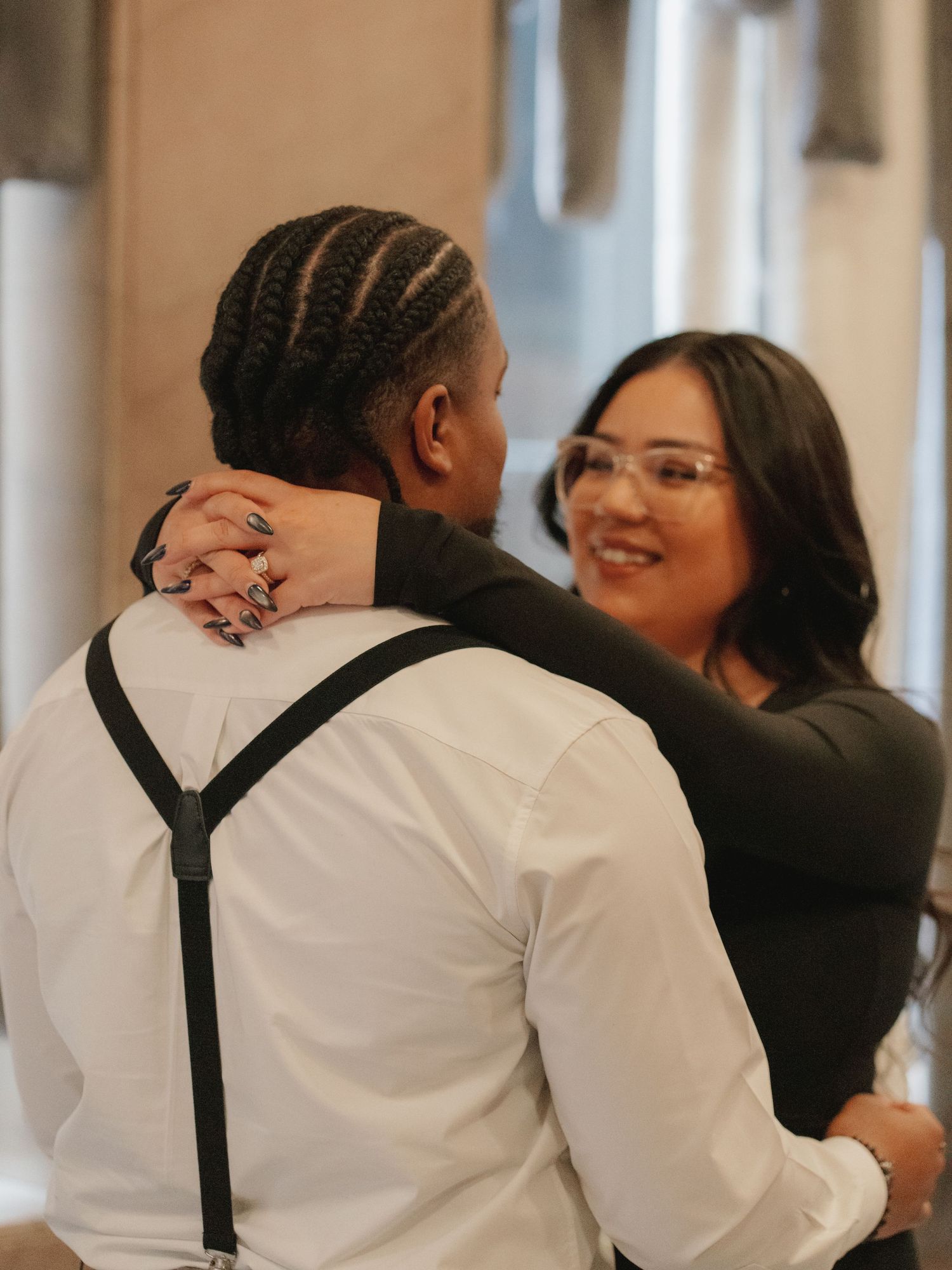 Couple sharing a tender dance moment, woman smiling with glasses, man in white shirt with suspenders.