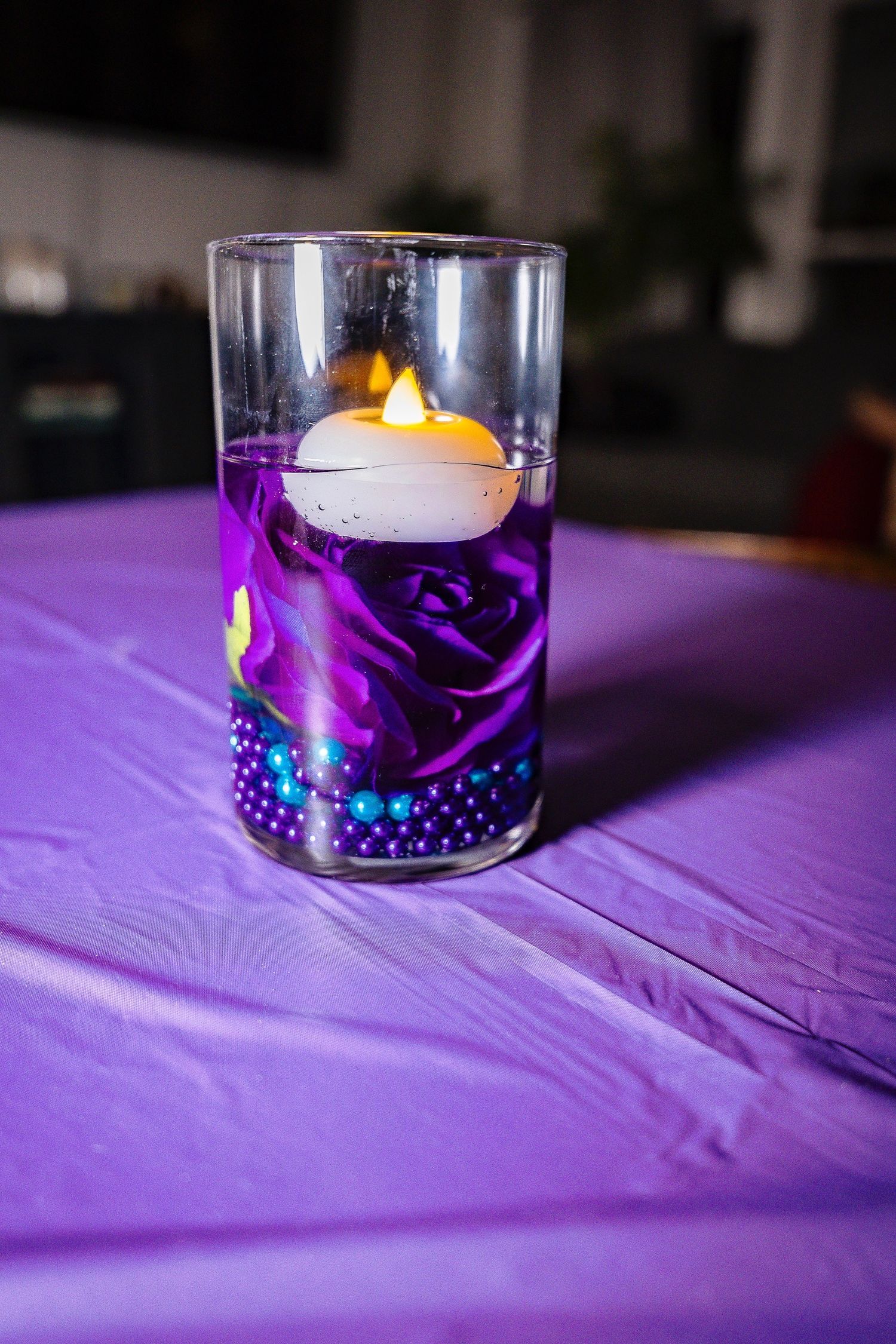 Purple and blue candle centerpieces with floating tea lights create an elegant ambiance at a formal event.