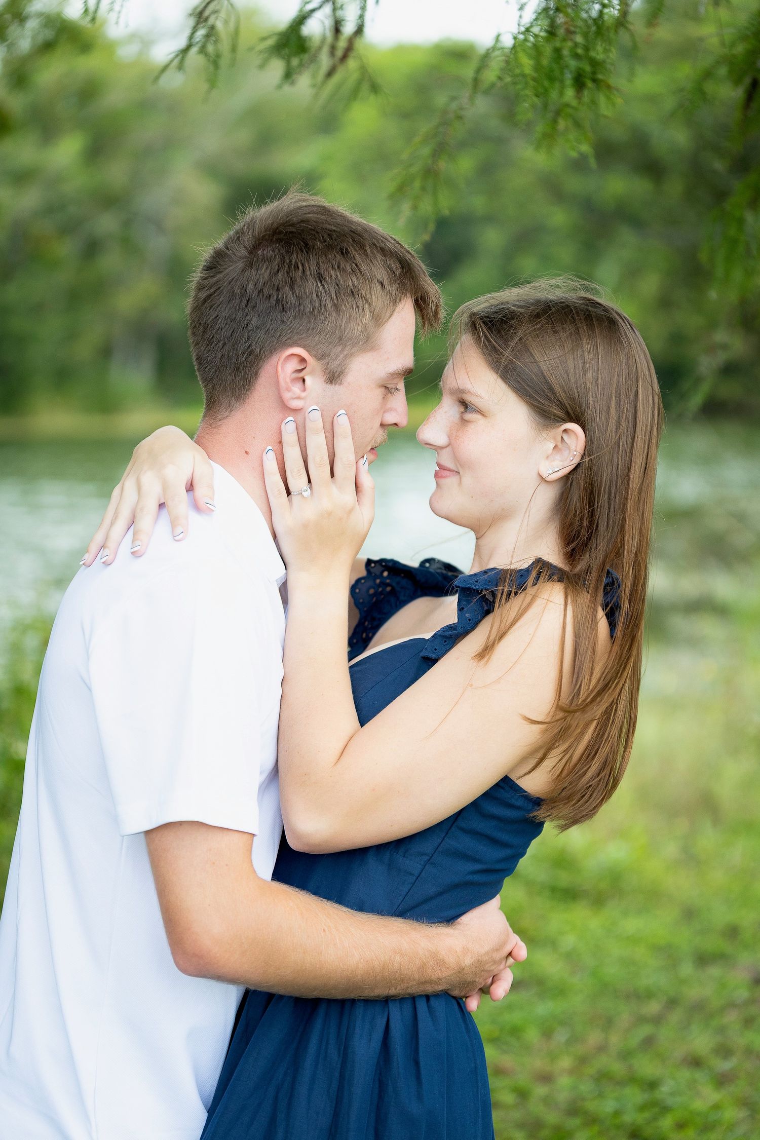 A romantic couple shares intimate moments in a lush green outdoor setting.