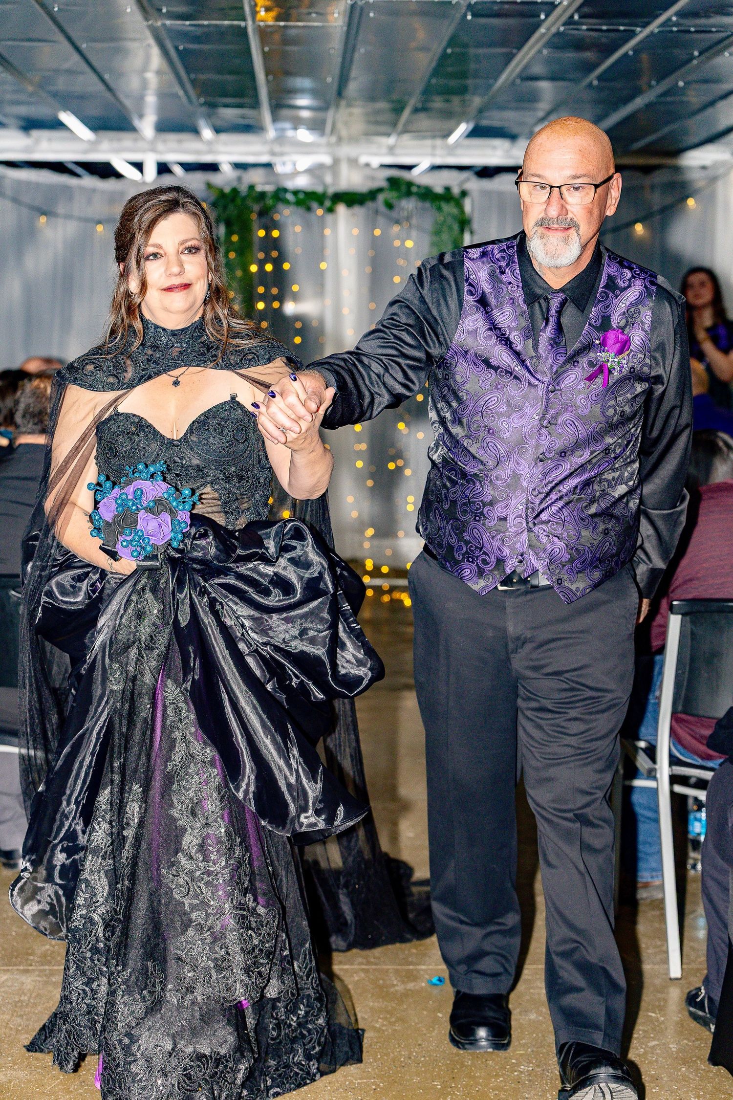 Couples dancing together at an indoor celebration with decorative lighting.