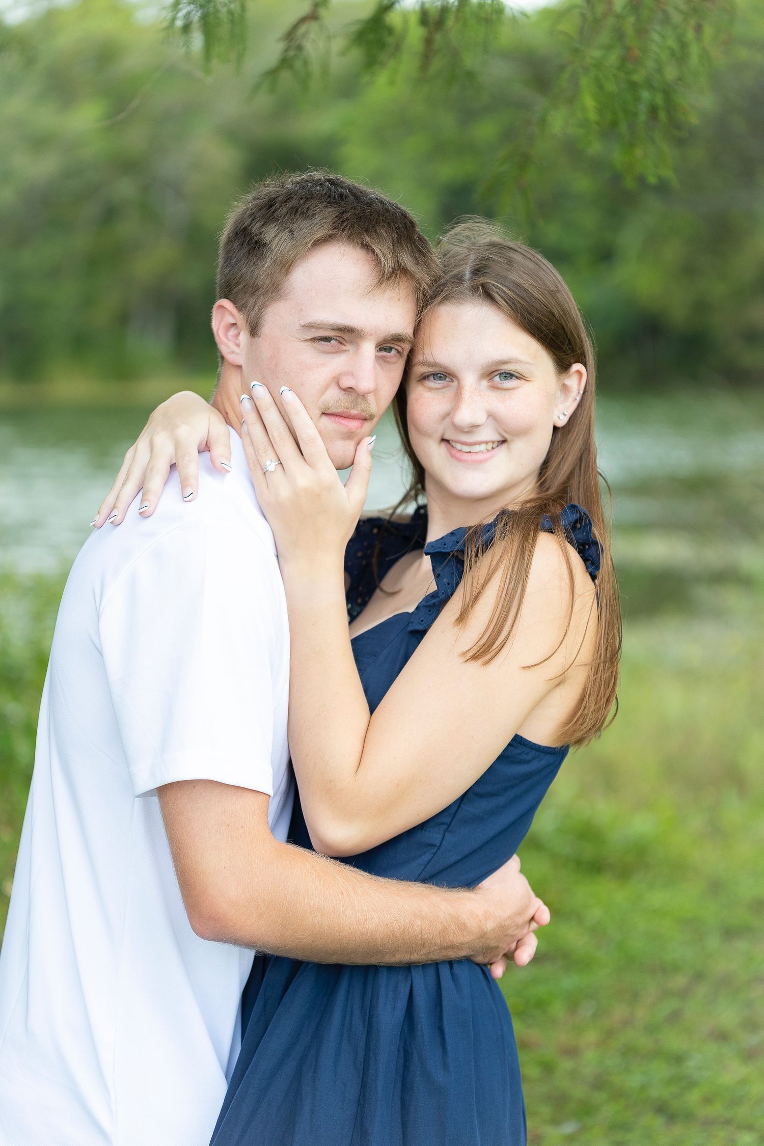 A couple embraces while sharing joyful moments in a sunlit outdoor setting.