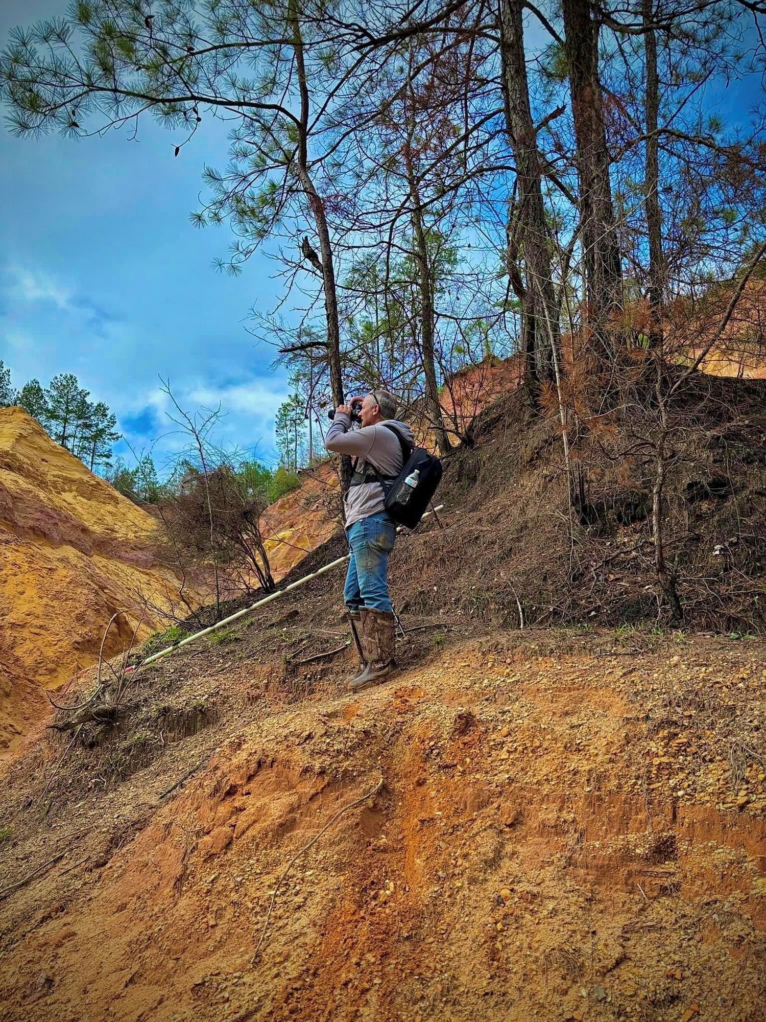 Series of action shots showing someone climbing up a steep red clay hillside among pine trees.