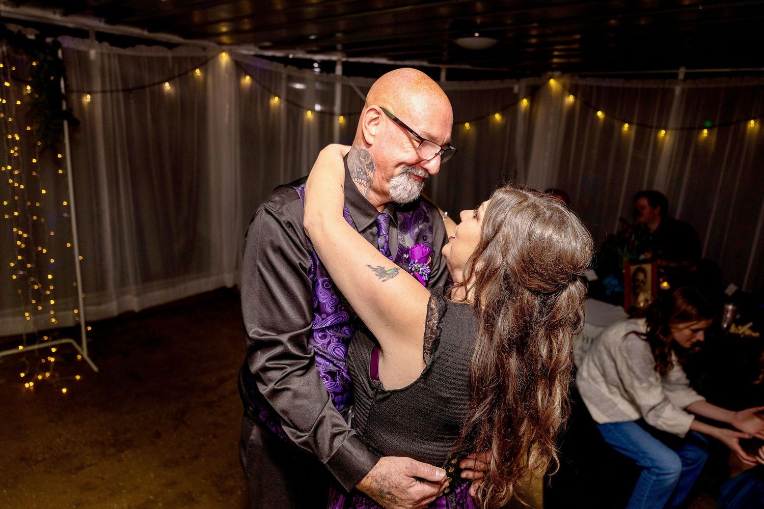 Couples dancing in a warmly lit venue with string lights.