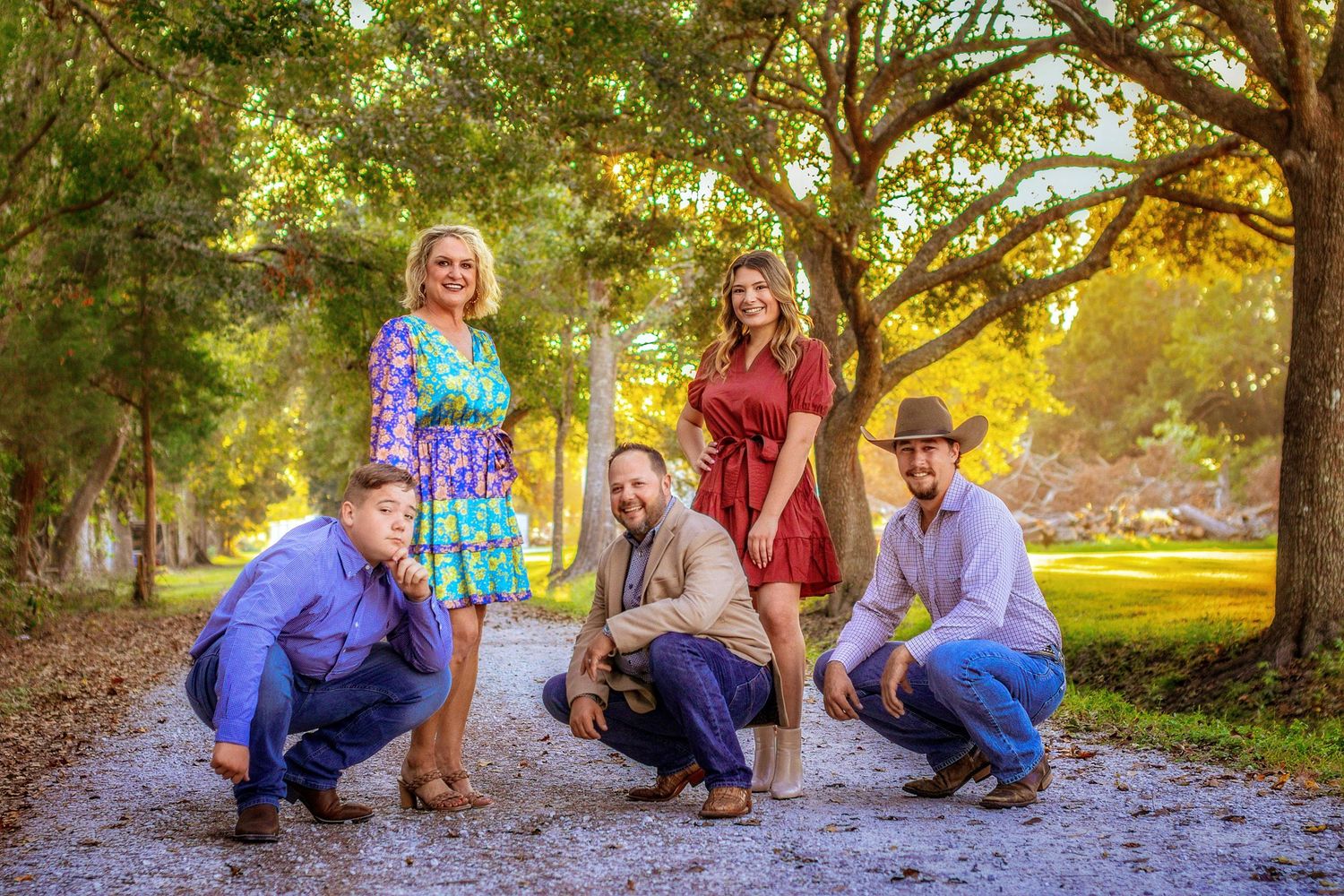 Family group photo session in a park during golden hour with autumn trees in the background.