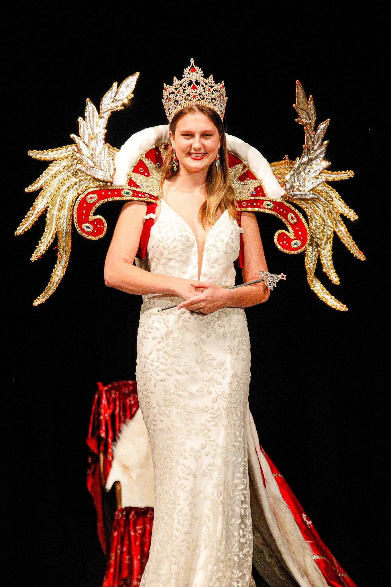 Elegant sequence in white lace dress with decorative gold wings against black background.