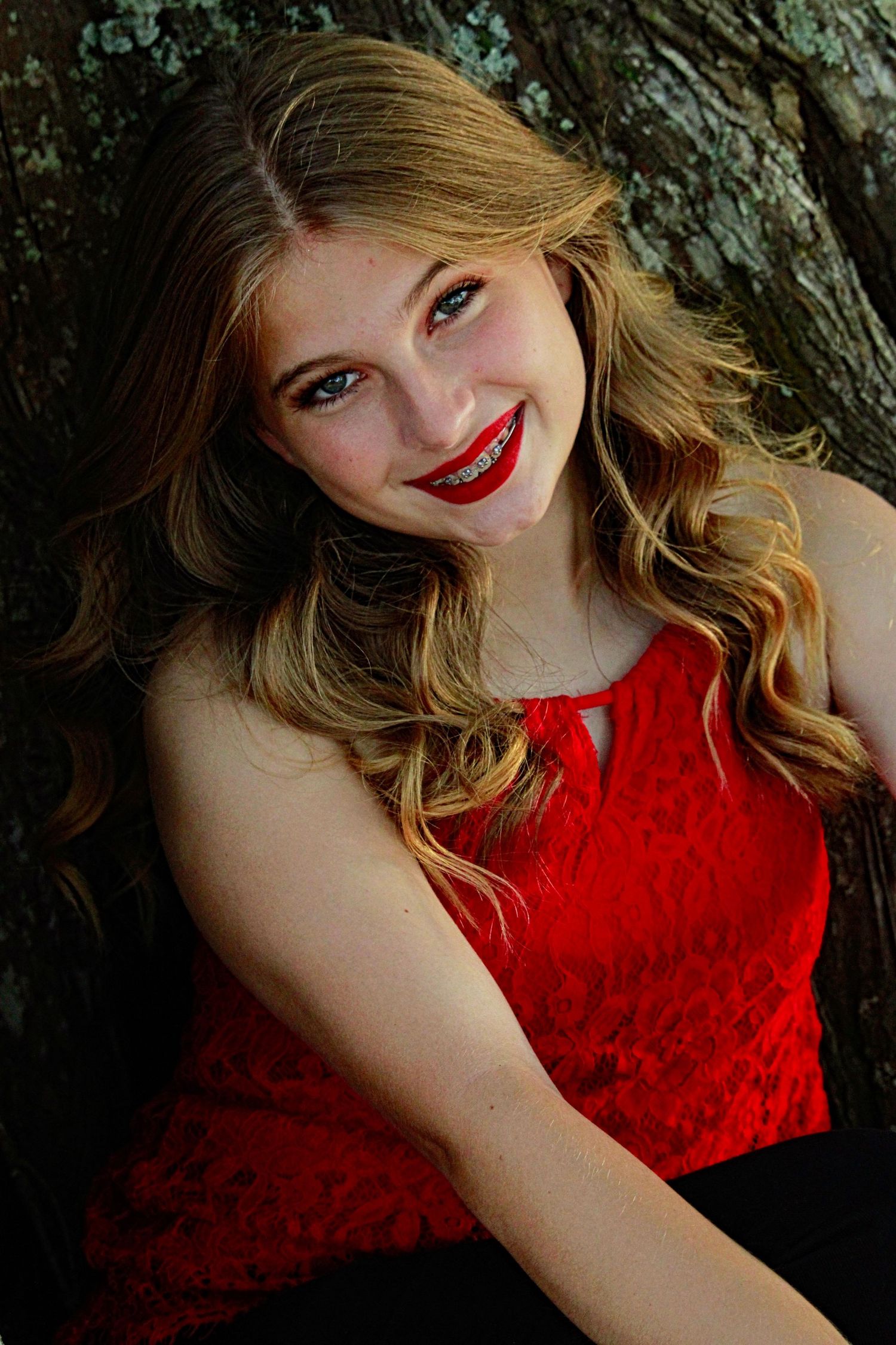 Artistic portrait series in red lace top against natural tree backdrop.