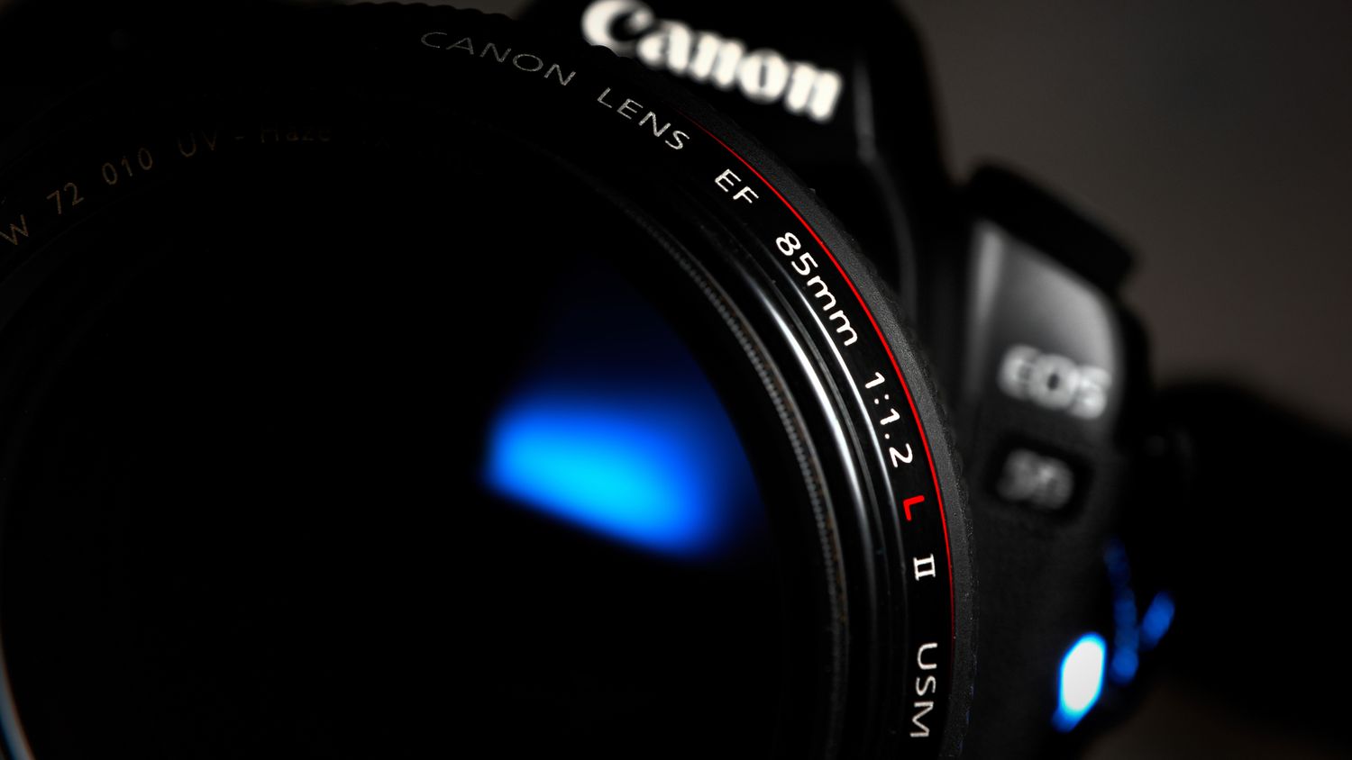 Close-up detail of Canon camera lens with blue reflection.