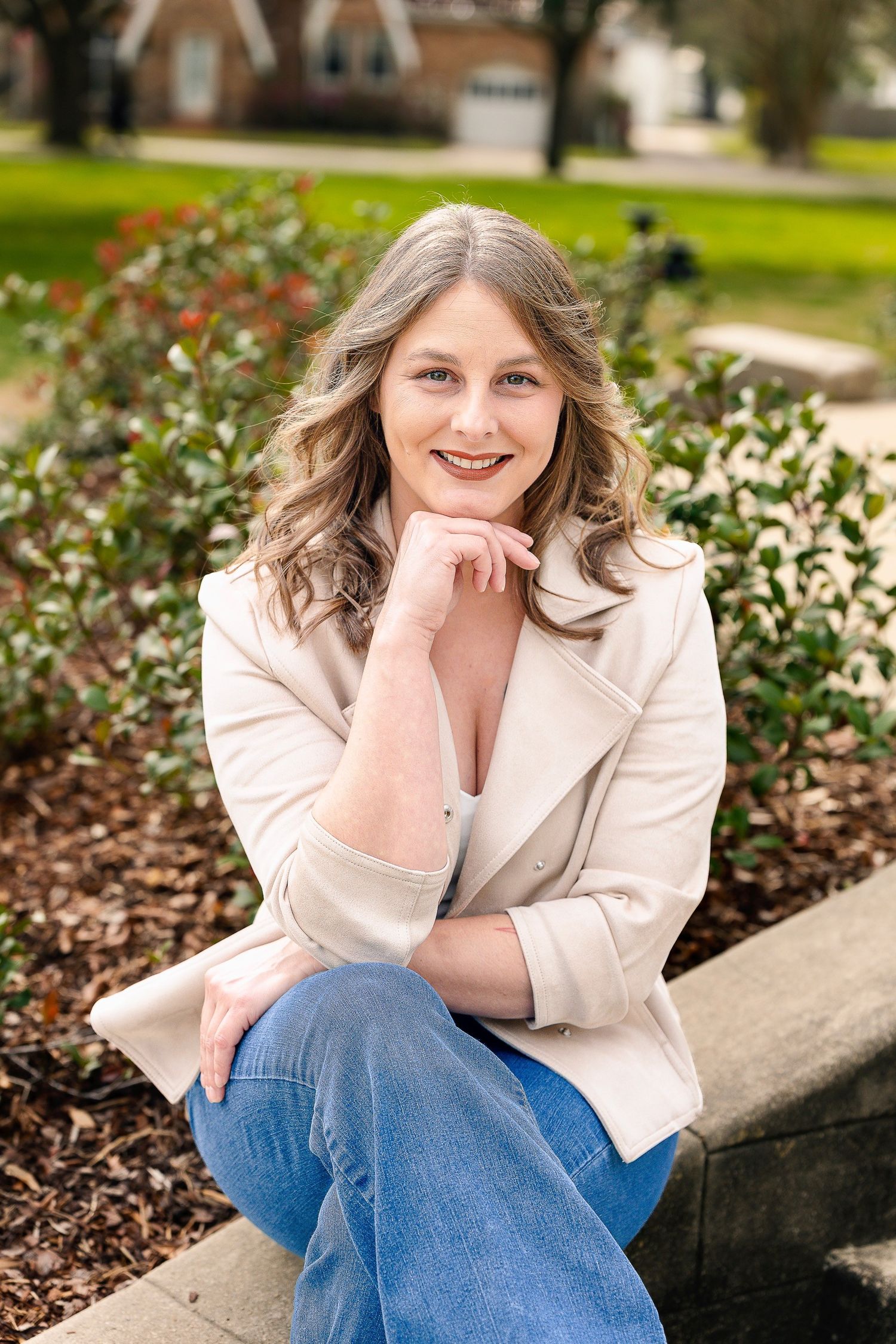 Outdoor portrait session in garden setting with cream blazer and casual denim.