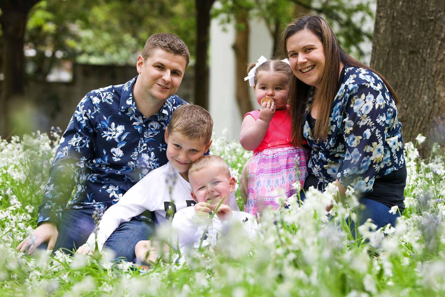 Family sitting together in a blooming spring garden surrounded by white flowers.