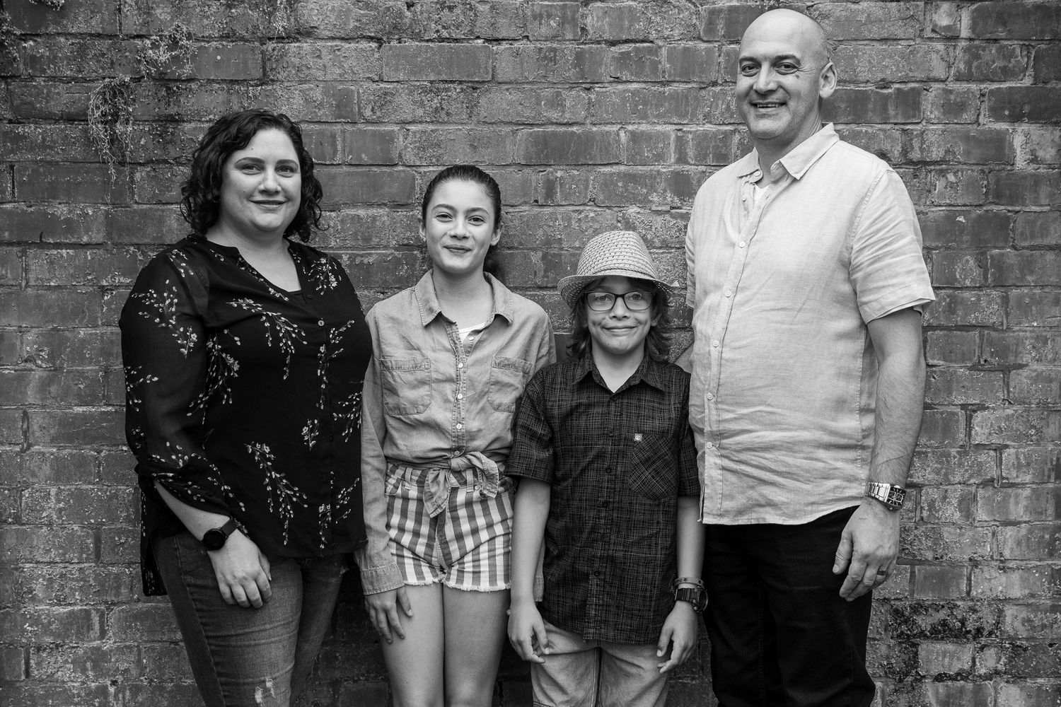 Group portrait against rustic brick wall background in casual attire.