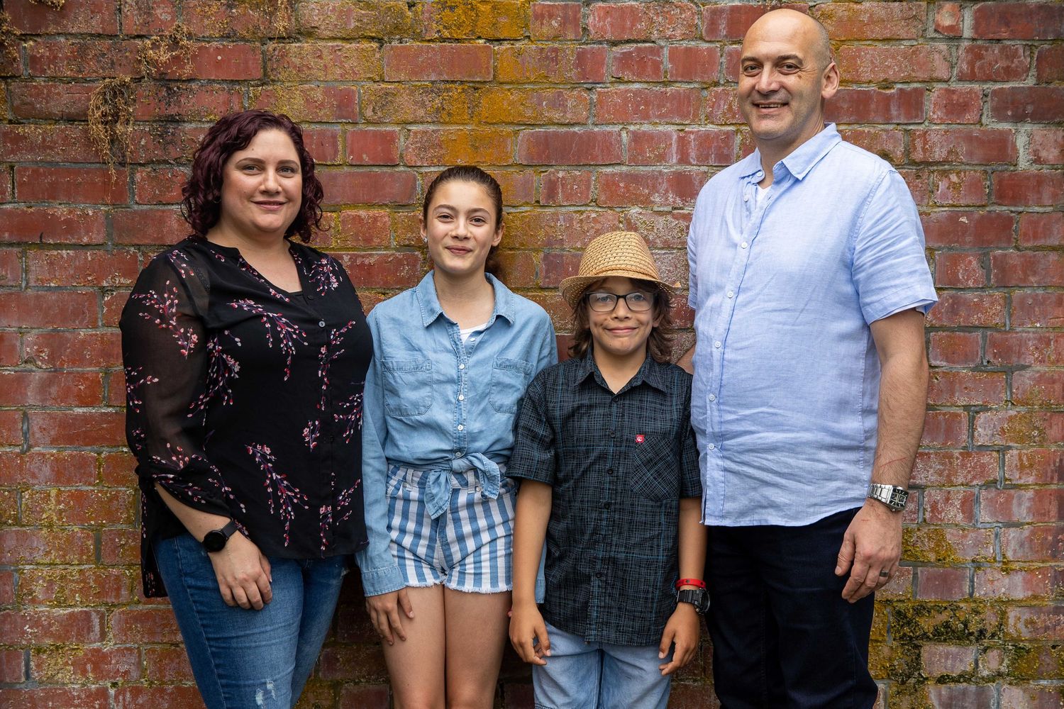 Casual group portrait against weathered brick wall background.